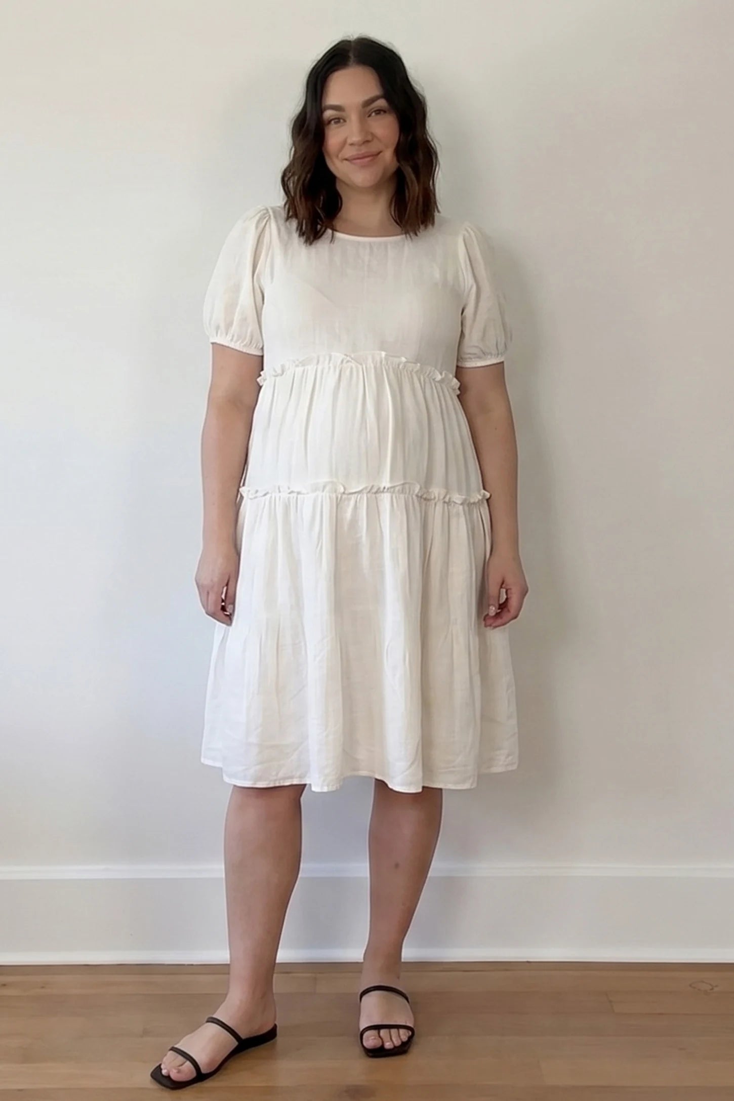 Puff Sleeve Tiered Midi Maternity Dress Puff Sleeve Tiered Midi Maternity Dress in Off-White featuring ruffled tiered skirt on a pregnant model, UGC view.