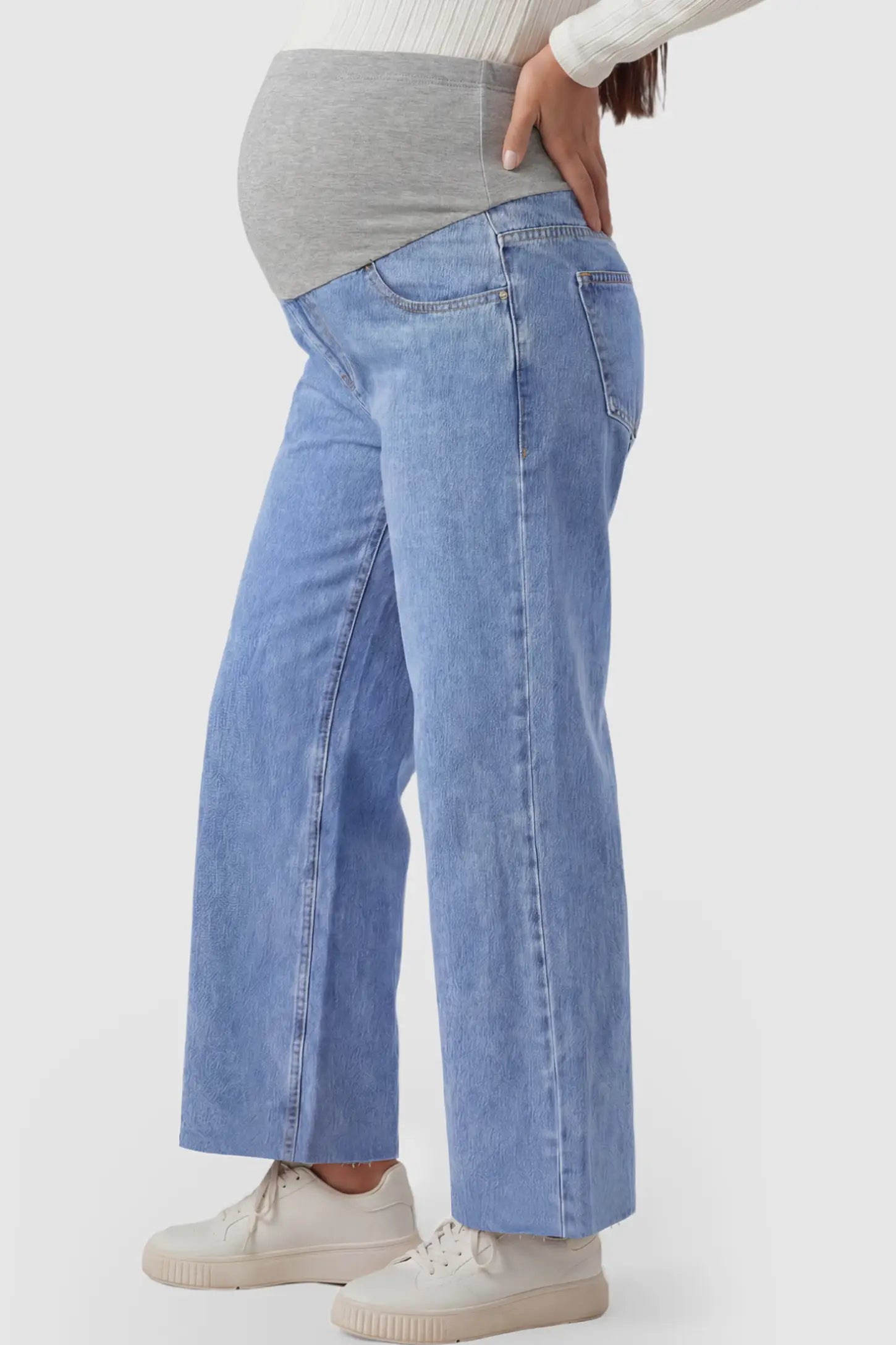 Raw Hem Full Panel Wide Leg Maternity Jeans Raw Hem Full Panel Wide Leg Maternity Jeans in light blue featuring a high-rise navy belly band on a pregnant model showing side.