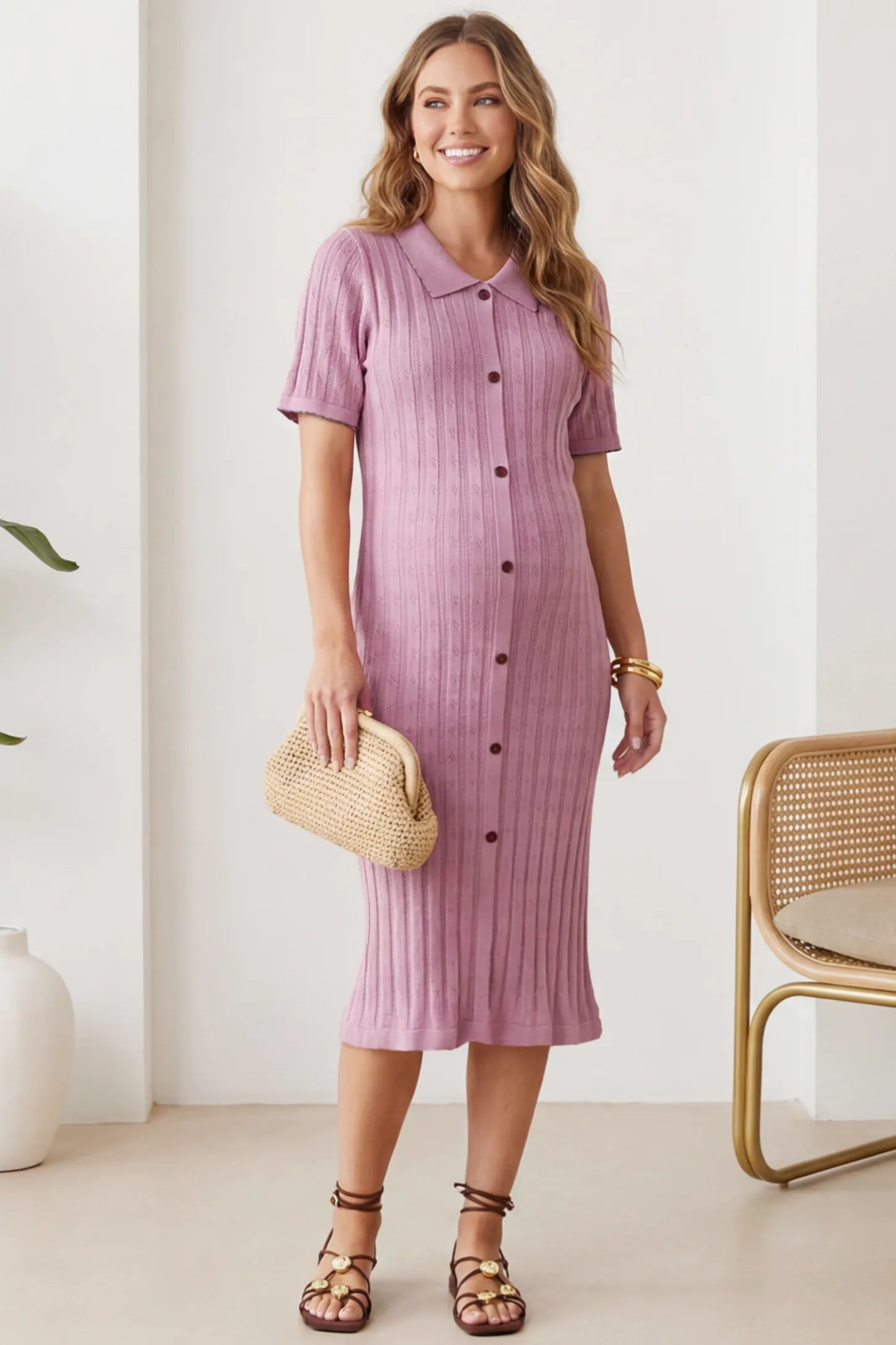 Ribbed Knit Collared Neck Maternity Midi Dress Ribbed Knit Collared Neck Maternity Midi Dress in Pink featuring short sleeves and soft knit high stretch fabric on a pregnant model at home styled with a clutch, front view.