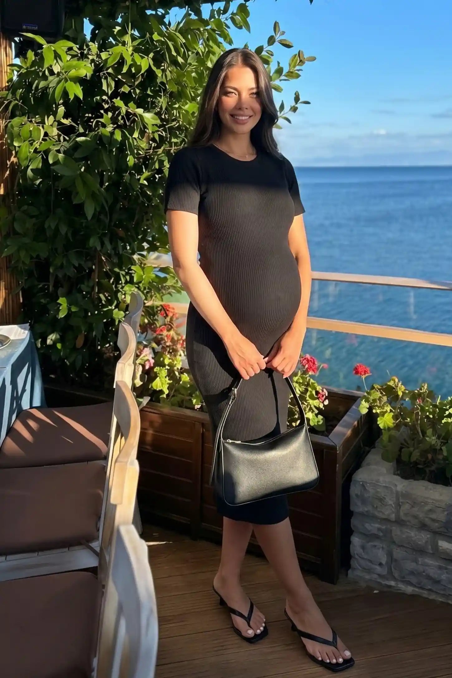 Ribbed Knit Short Sleeve Midi Maternity Dress Ribbed Knit Short Sleeve Midi Maternity Dress in Black featuring a midi-length stretch fit on a pregnant model in an editorial setting.