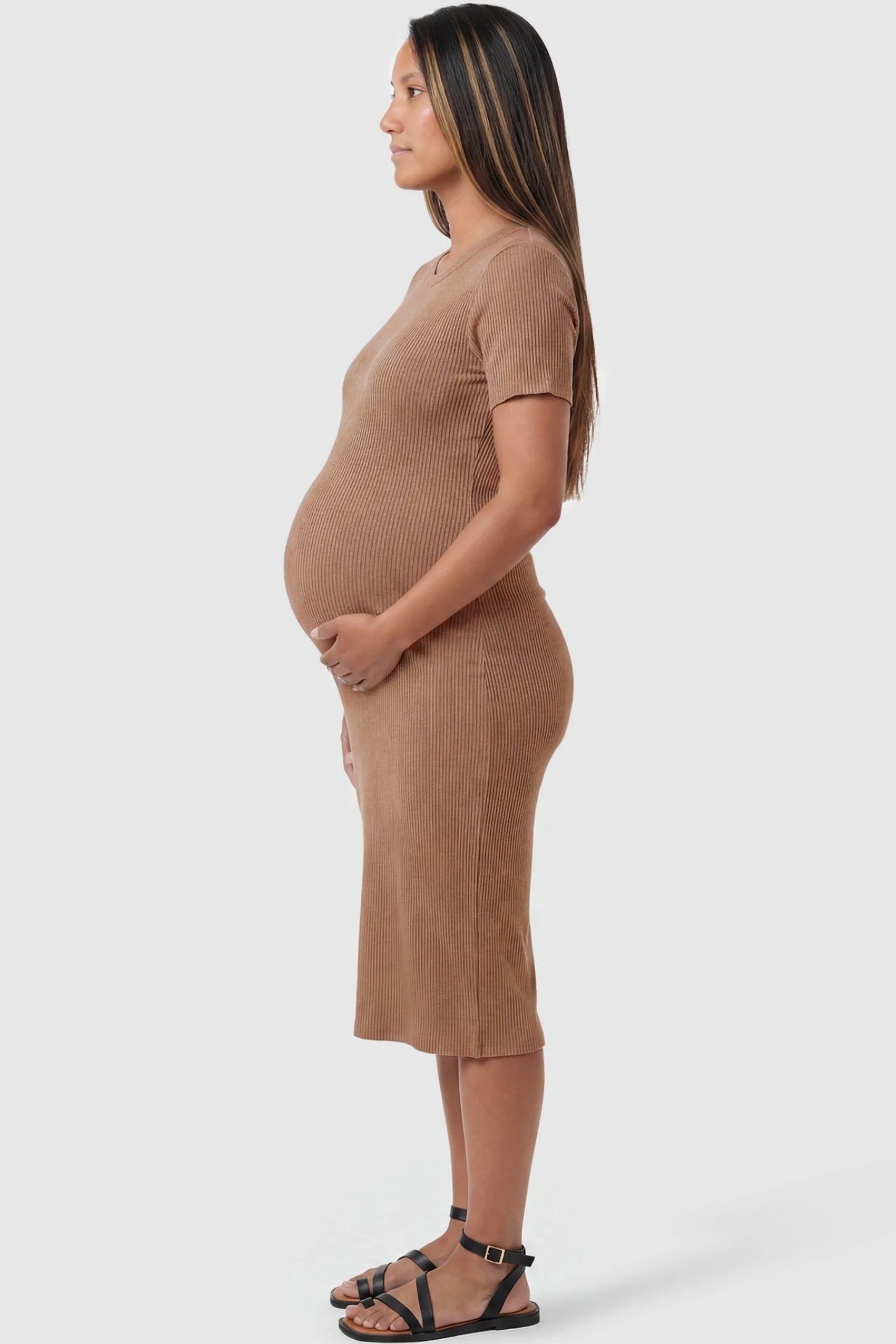 Ribbed Knit Short Sleeve Midi Maternity Dress Ribbed Knit Short Sleeve Midi Maternity Dress in Khaki featuring a stretchy bump-hugging silhouette on a pregnant model, side view.