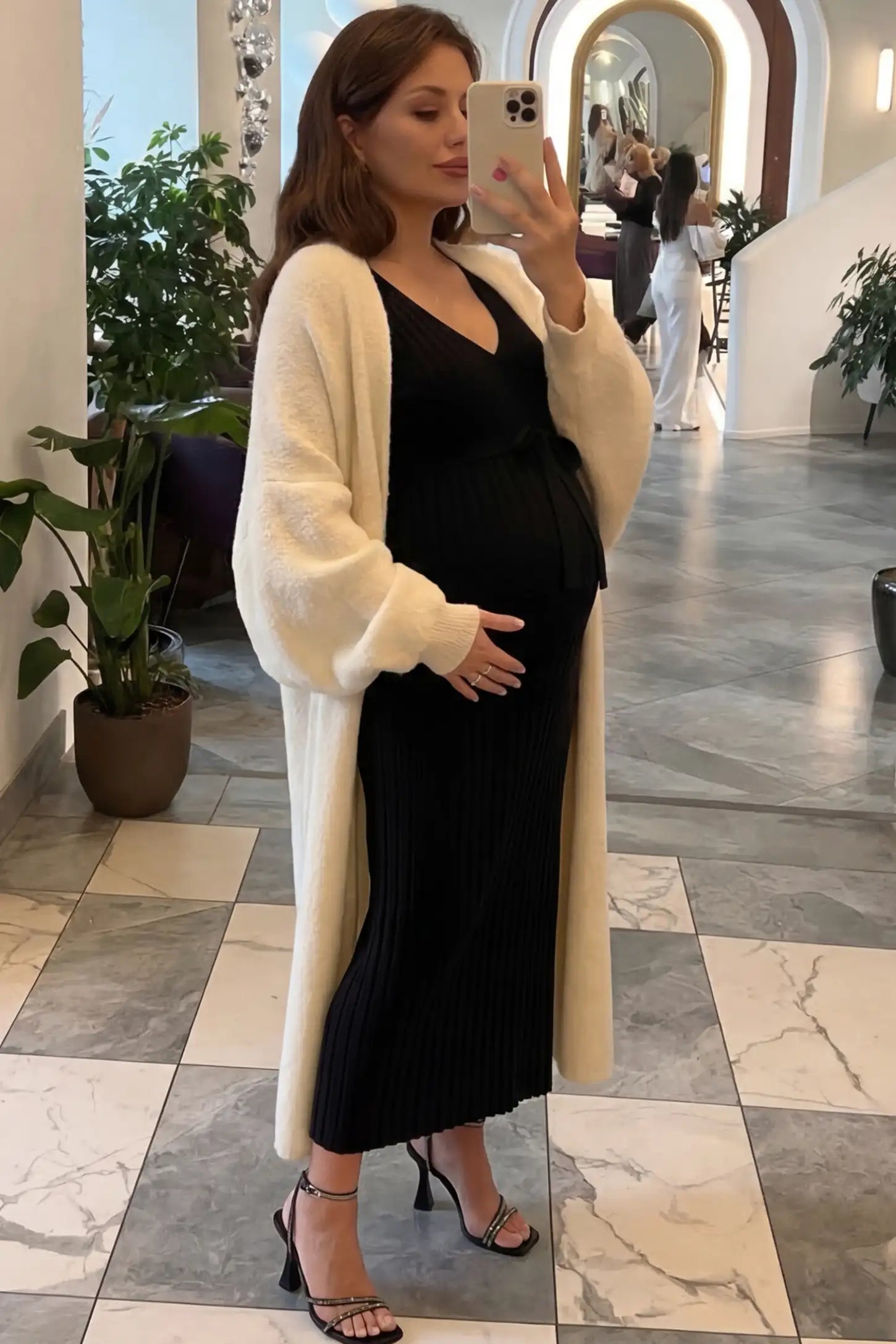 Ribbed Knit V-Neck Tie Waist Maternity Maxi Dress Ribbed knit maternity maxi dress in black featuring a V-neck and tie waist on a model in an indoor setting, side view.
