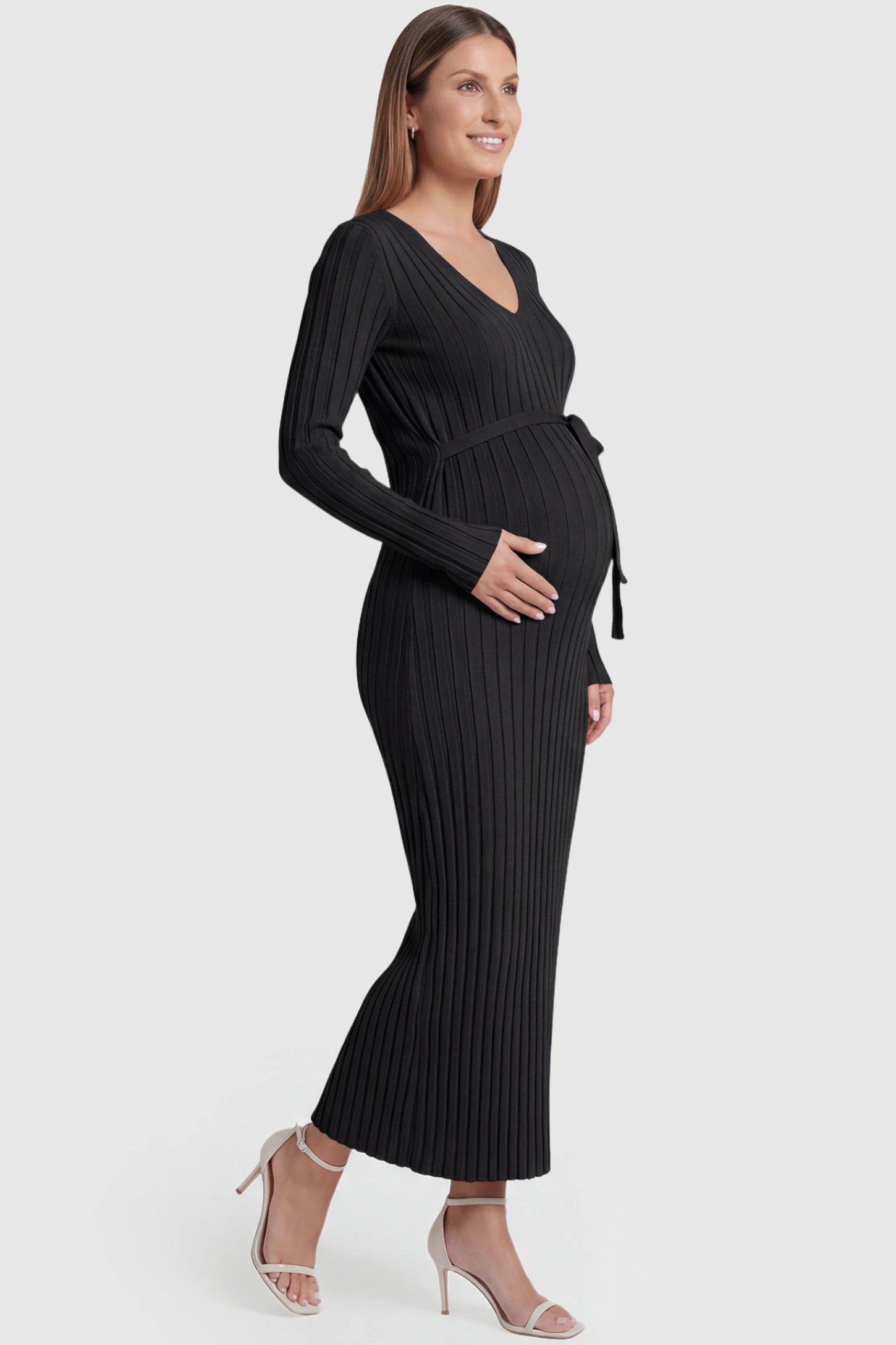 Ribbed Knit V-Neck Tie Waist Maternity Maxi Dress Ribbed Knit V-Neck Maternity Maxi Dress in Black featuring a tie waist and long sleeves on a pregnant model, side view.