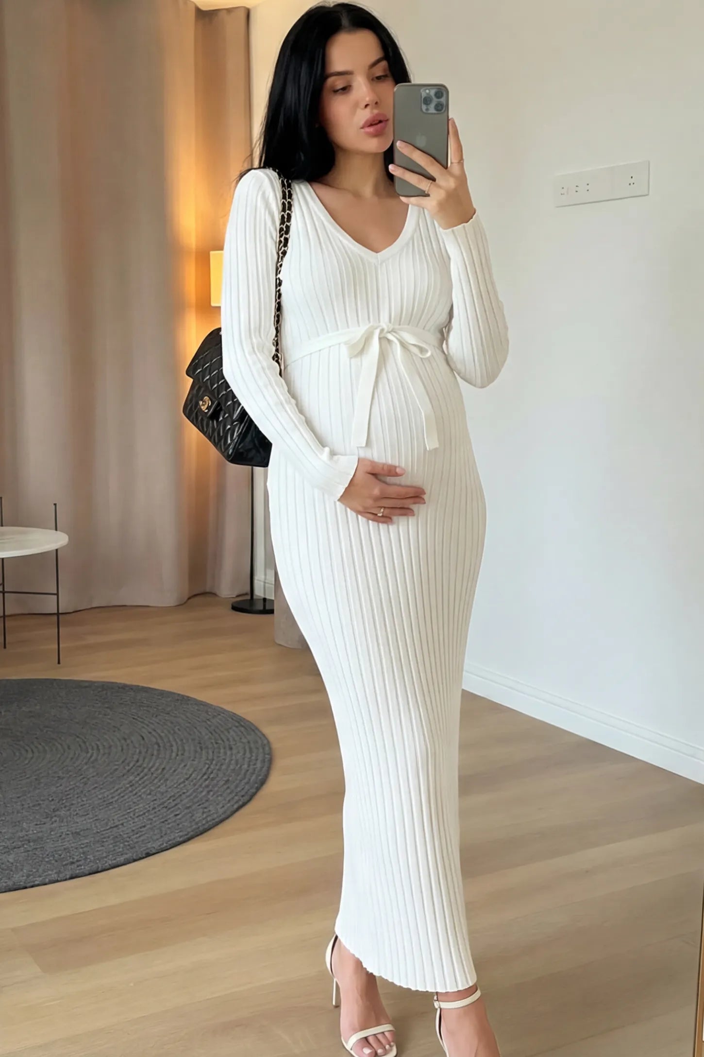 Ribbed Knit V-Neck Tie Waist Maternity Maxi Dress Ribbed knit maternity maxi dress in white featuring a V-neck and tie waist on a model in an indoor setting, front view.