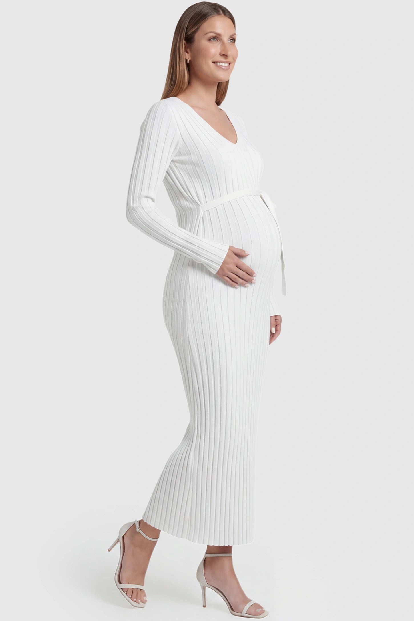 Ribbed Knit V-Neck Tie Waist Maternity Maxi Dress Ribbed Knit V-Neck Maternity Maxi Dress in White featuring a tie waist and long sleeves on a pregnant model, side view.
