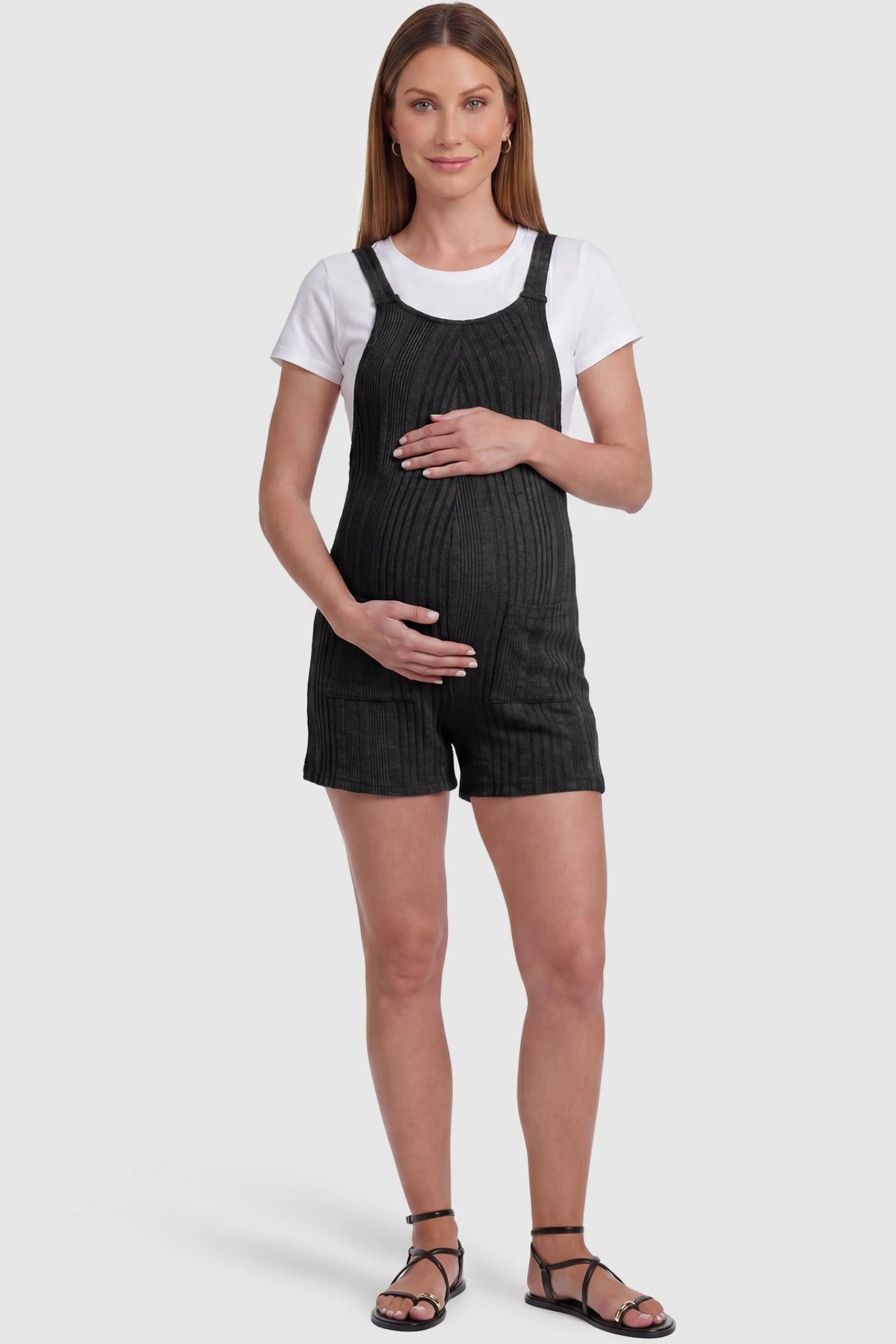 Ribbed Pocket Knit Maternity Romper Ribbed Pocket Knit Romper in Black featuring a classic vertical ribbed texture on a pregnant model, front view.