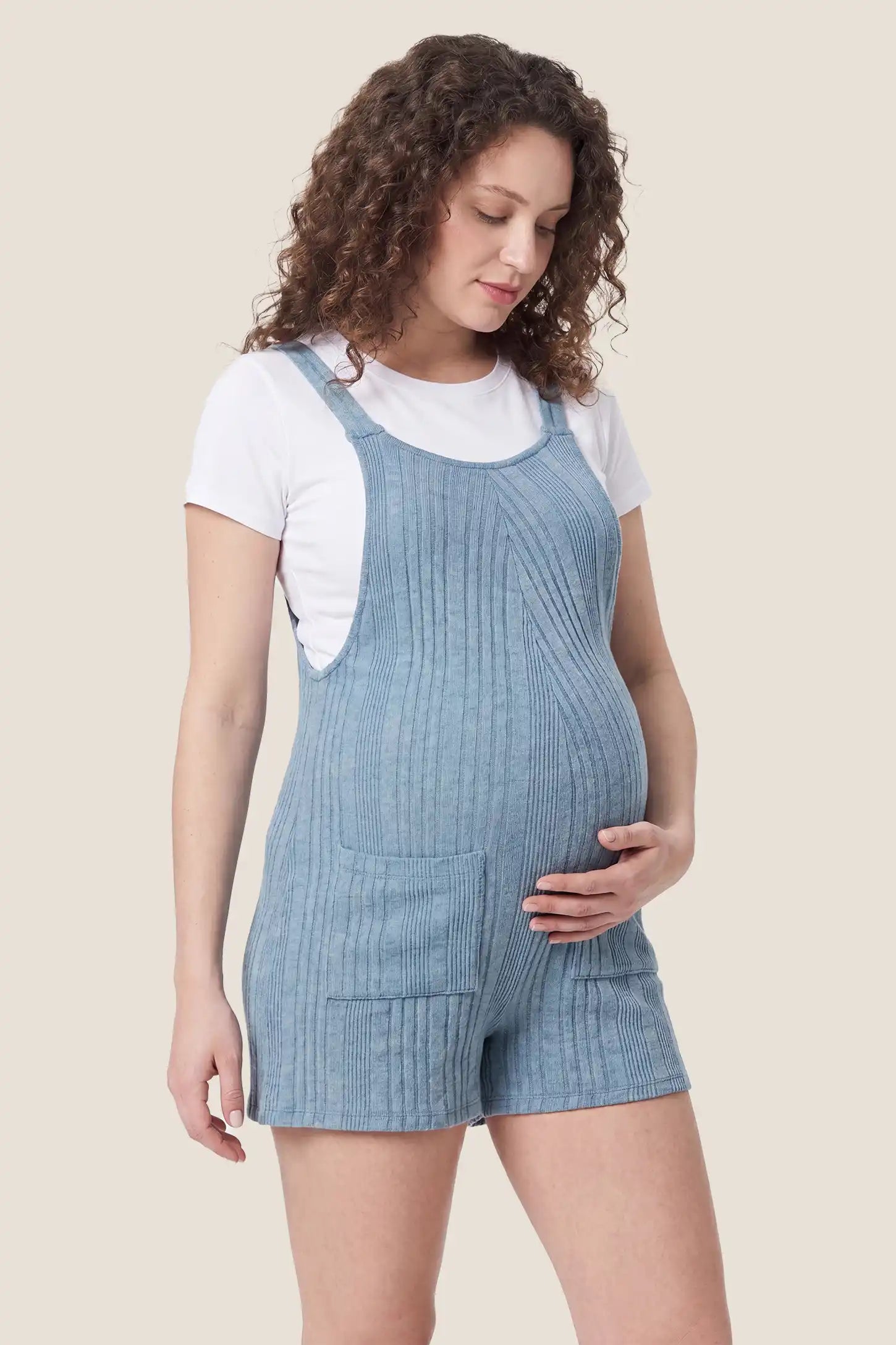 Ribbed Pocket Knit Romper in Blue featuring a flexible ribbed knit fabric on a pregnant model, side view.
