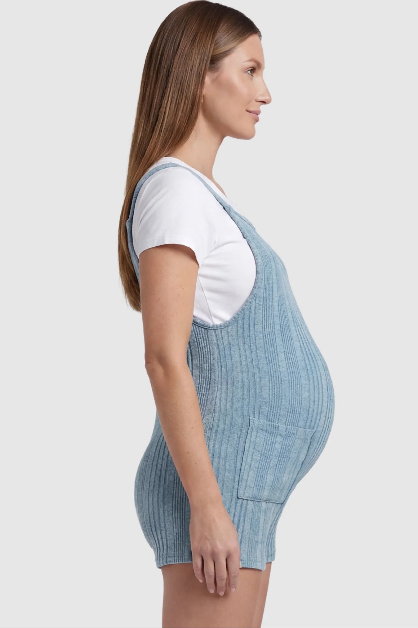 Ribbed Pocket Knit Maternity Romper Ribbed Pocket Knit Romper in Blue featuring a flexible ribbed knit fabric on a pregnant model, side view.