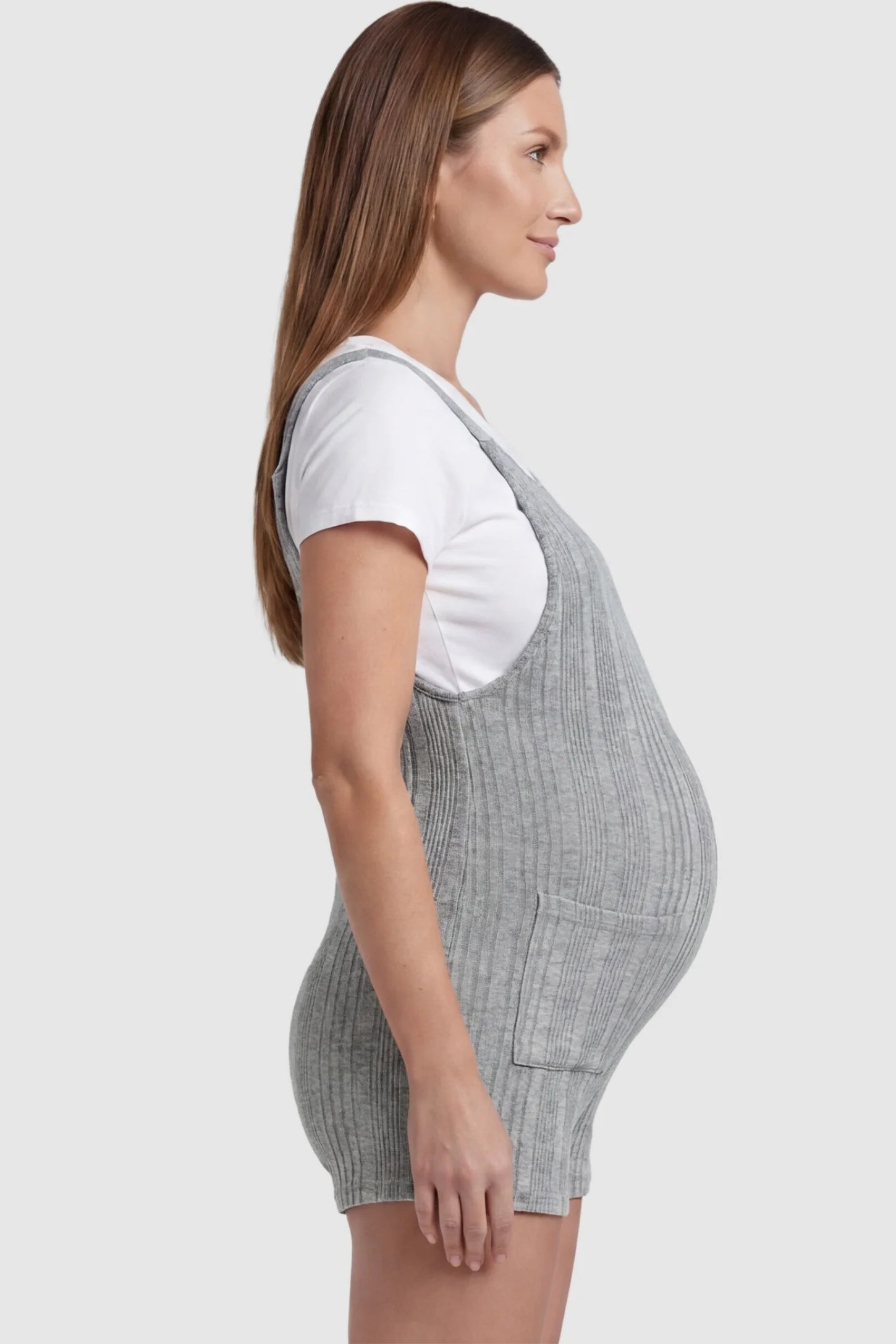 Ribbed Pocket Knit Maternity Romper Ribbed Pocket Knit Romper in Gray featuring a flexible ribbed knit fabric on a pregnant model, side view.