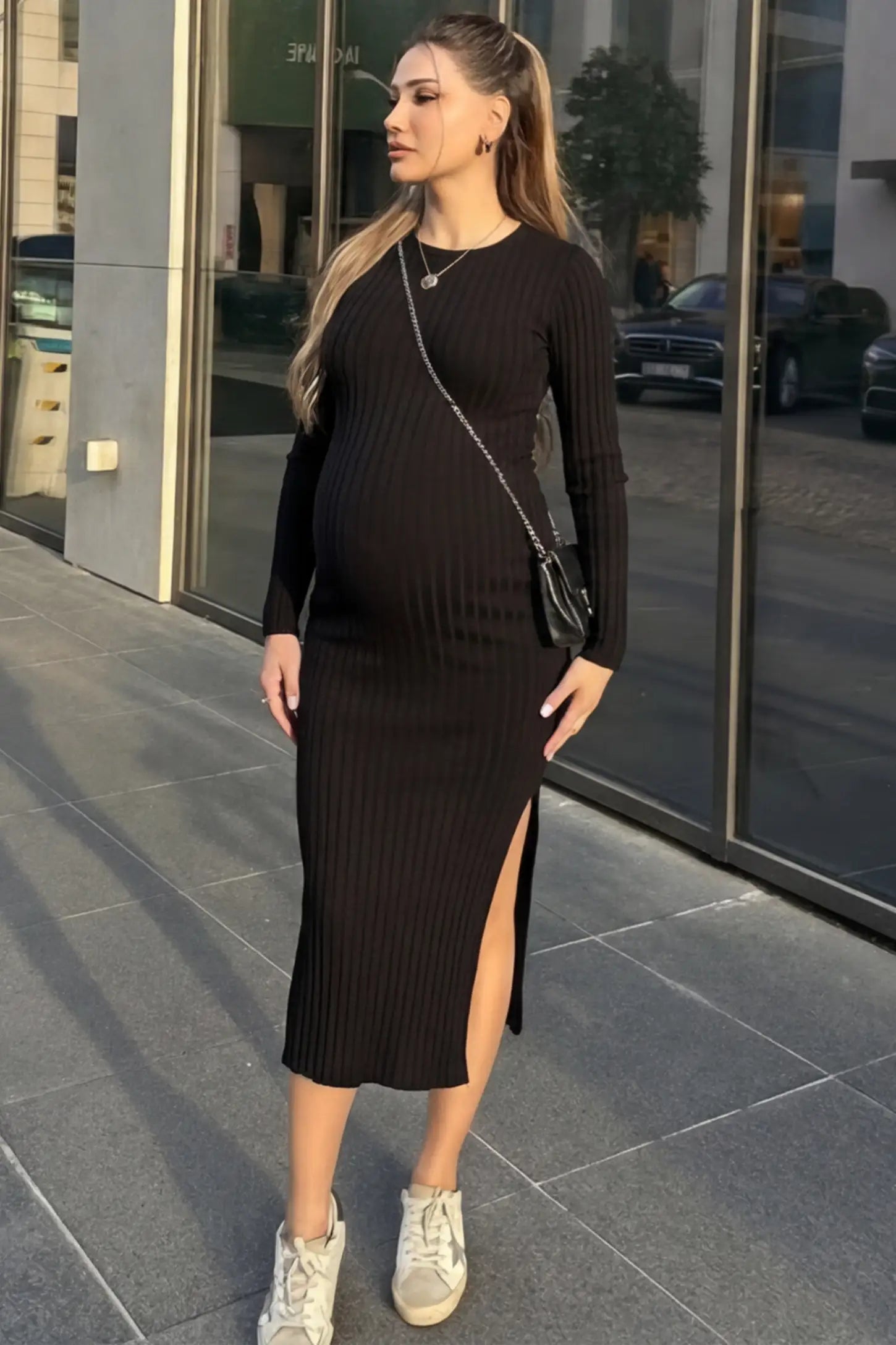 Ribbed Side Slit Fitted Long Sleeve Maternity Maxi Dress Ribbed Side Slit Fitted Long Sleeve Maternity Maxi Dress in Black featuring a high side slit on a pregnant woman in outdoor setting, front view.