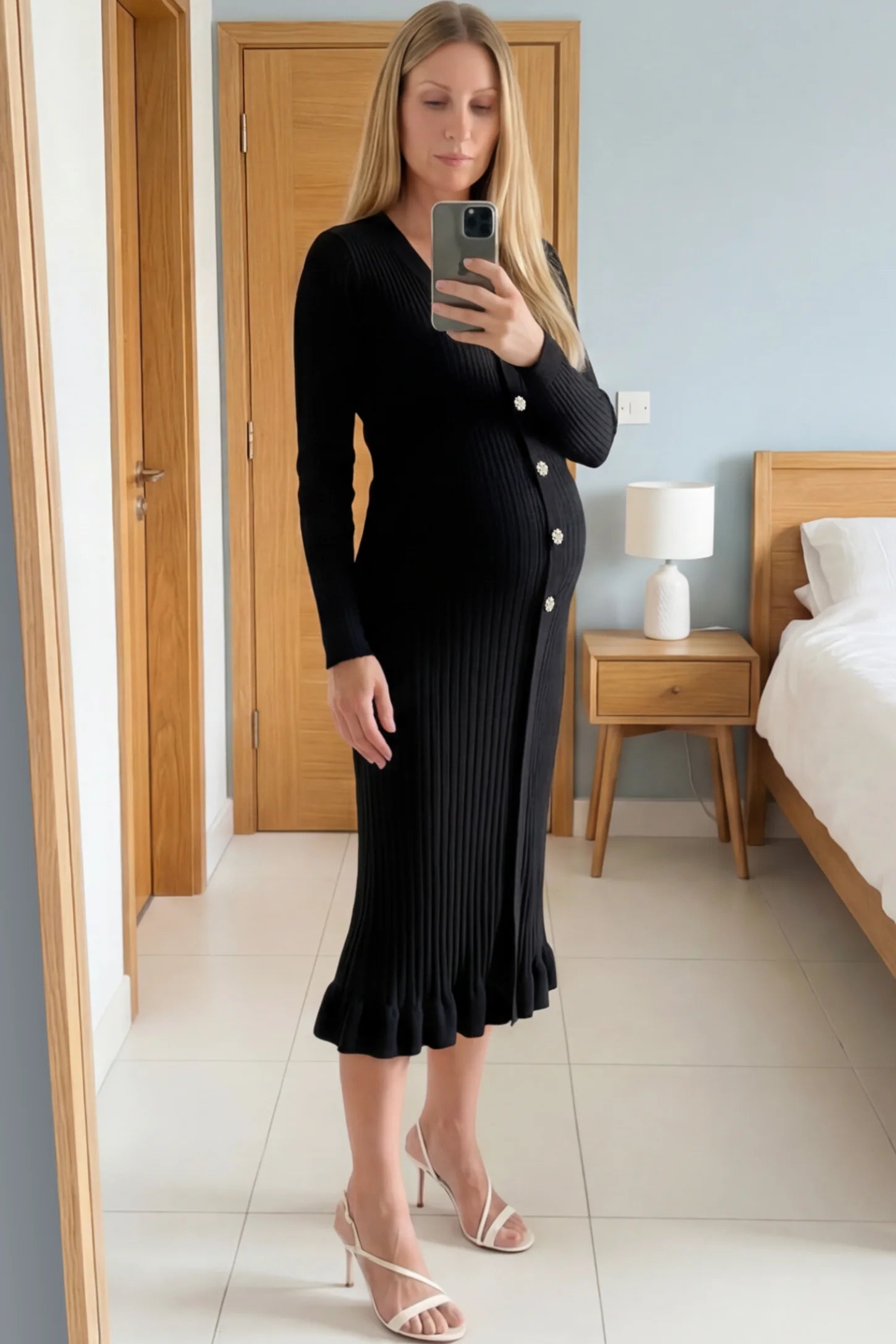 Ribbed V-Neck Maternity Midi Sweater Dress Ribbed V-Neck Maternity Midi Sweater Dress in Black featuring rhinestone buttons on a pregnant woman showing front.