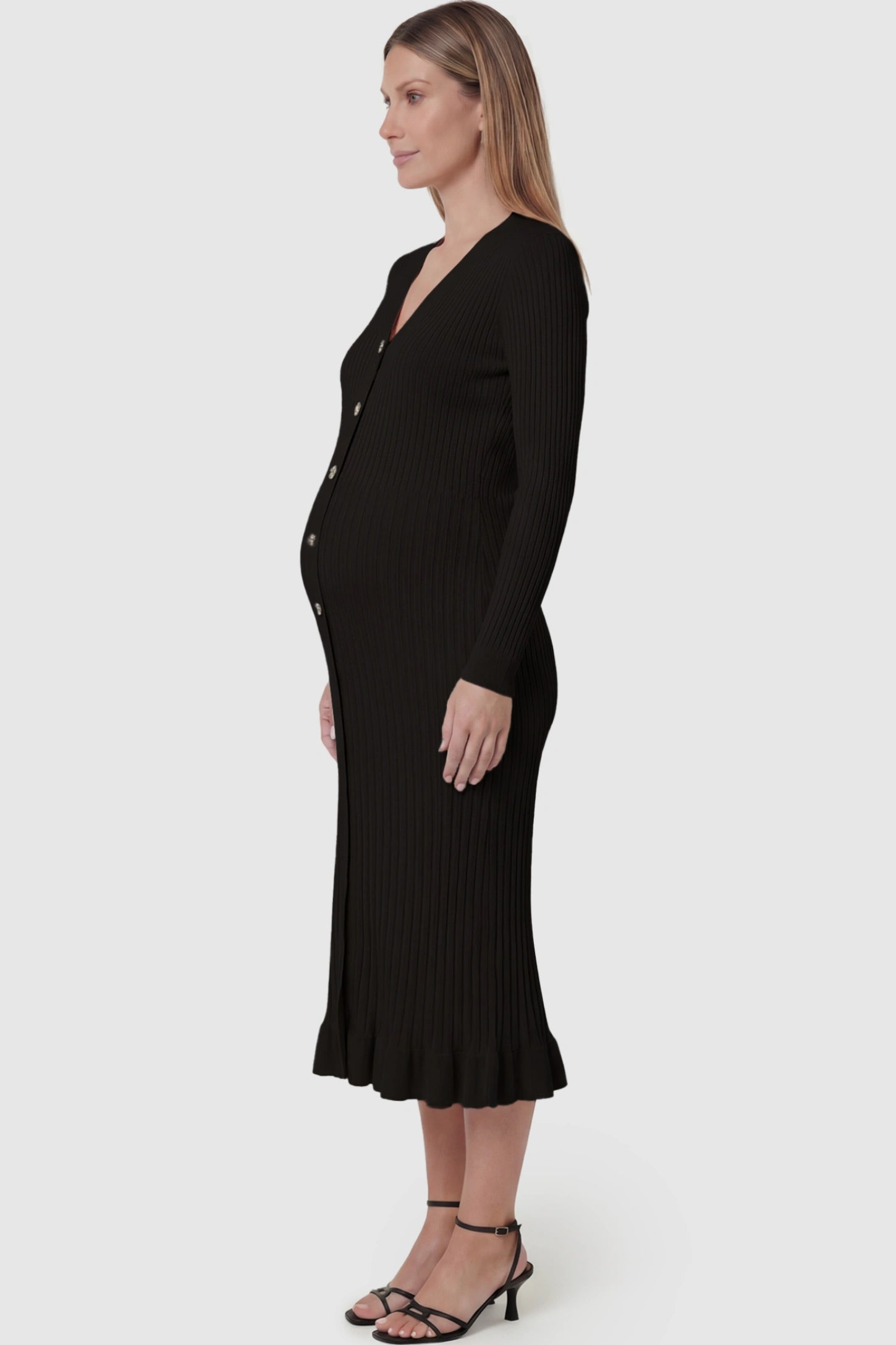Ribbed V-Neck Maternity Midi Sweater Dress Ribbed V-Neck Maternity Midi Sweater Dress in Black featuring rhinestone buttons on a pregnant model showing side.