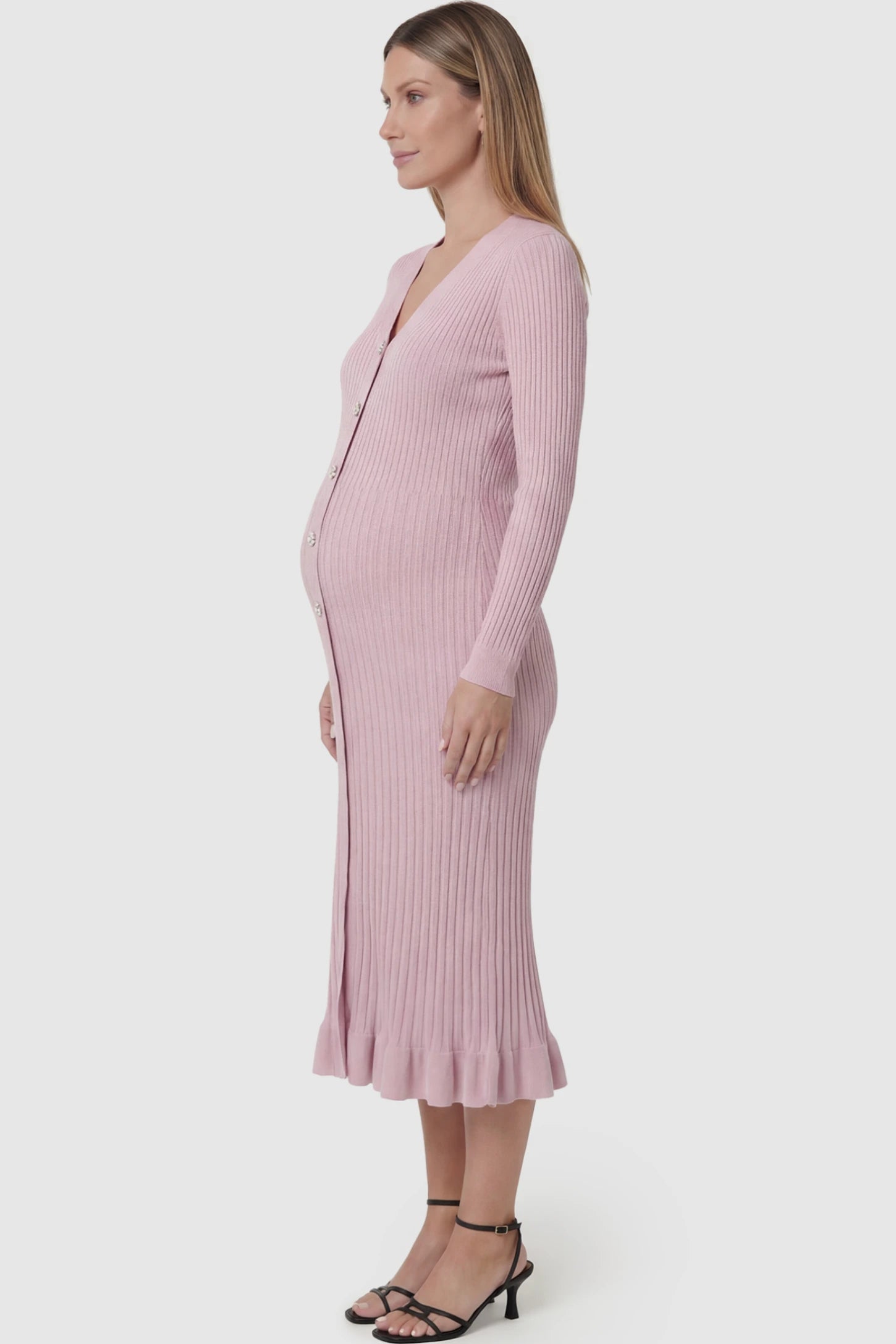Ribbed V-Neck Maternity Midi Sweater Dress Ribbed V-Neck Maternity Midi Sweater Dress in Pink featuring rhinestone buttons on a pregnant model showing side.