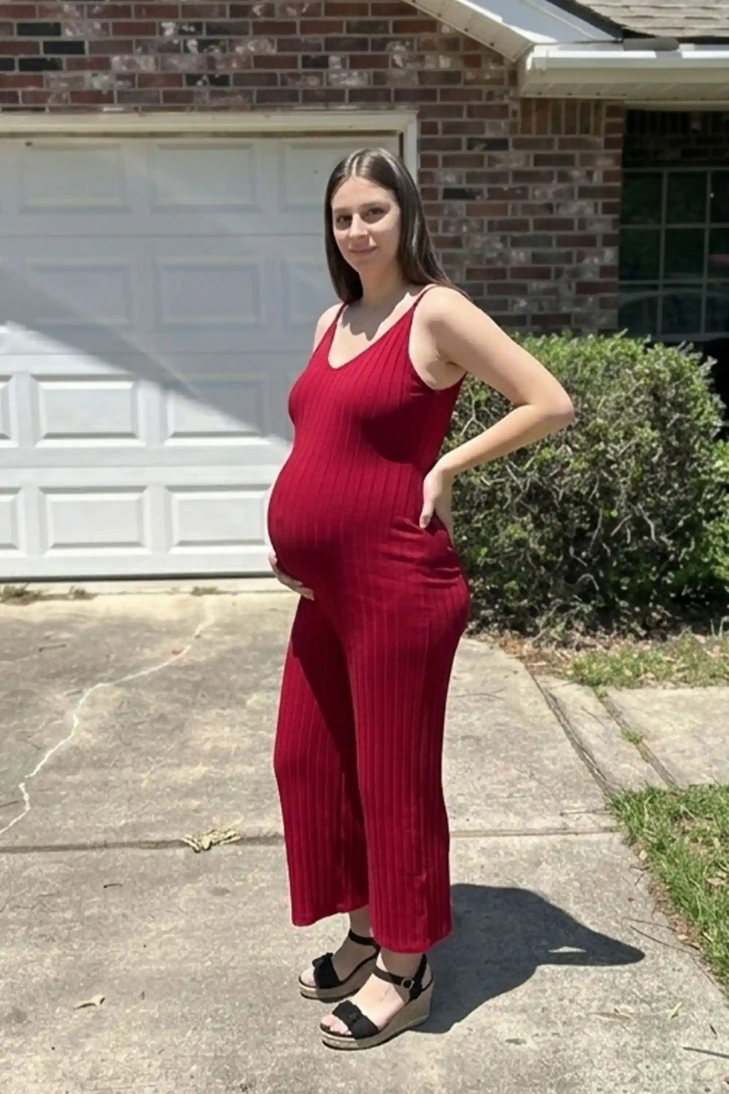 Ribbed Wide-Leg Maternity Camisole Jumpsuit Ribbed Wide-Leg Maternity Camisole Jumpsuit in Red featuring an effortless ribbed design and wide leg on a pregnant model, UGC view.