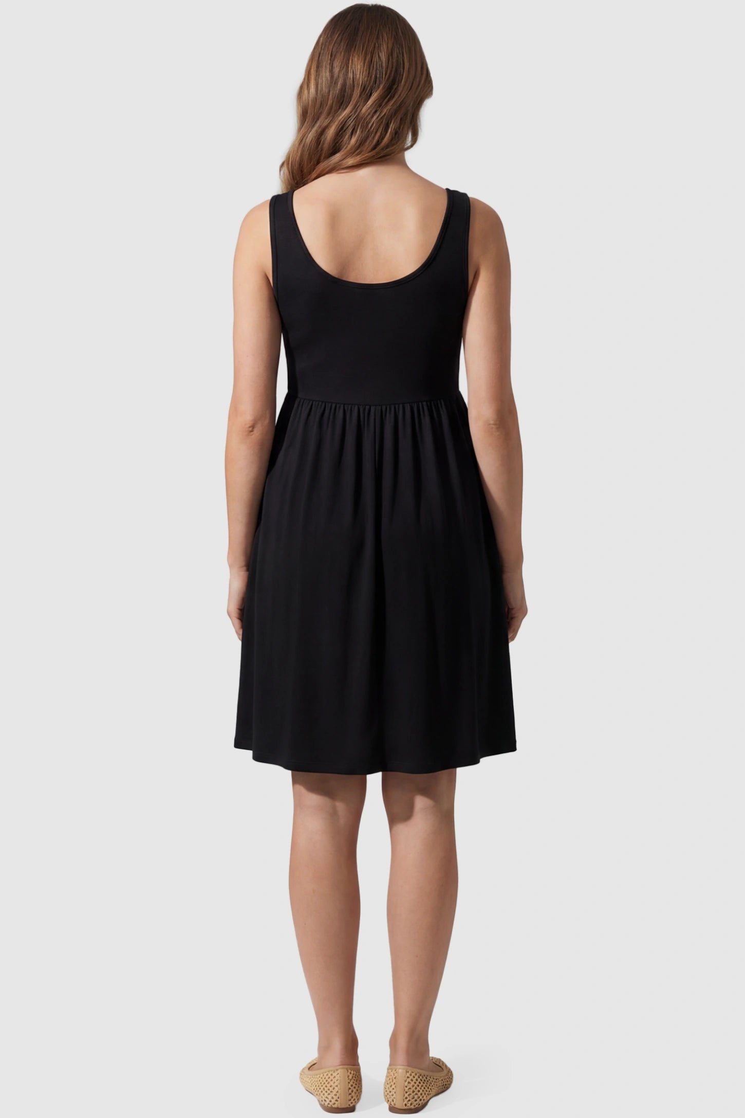 Round Neck Empire Waist Maternity Short Dress Round Neck Empire Waist Maternity Short Dress in Black featuring soft knit stretch on a pregnant model, back view.