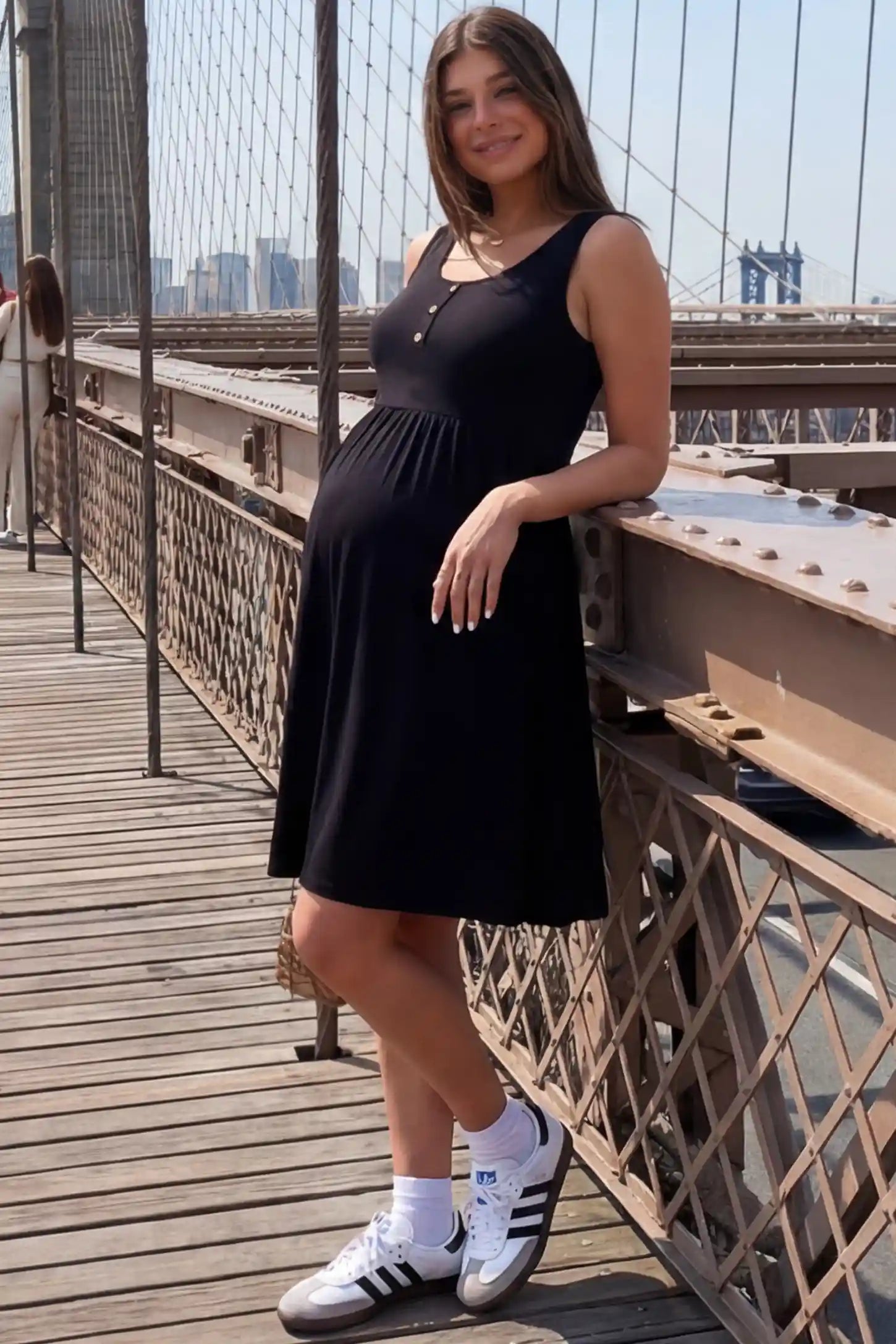 Round Neck Empire Waist Maternity Short Dress in Black featuring soft knit stretch on a pregnant woman in outdoor setting, side view.
