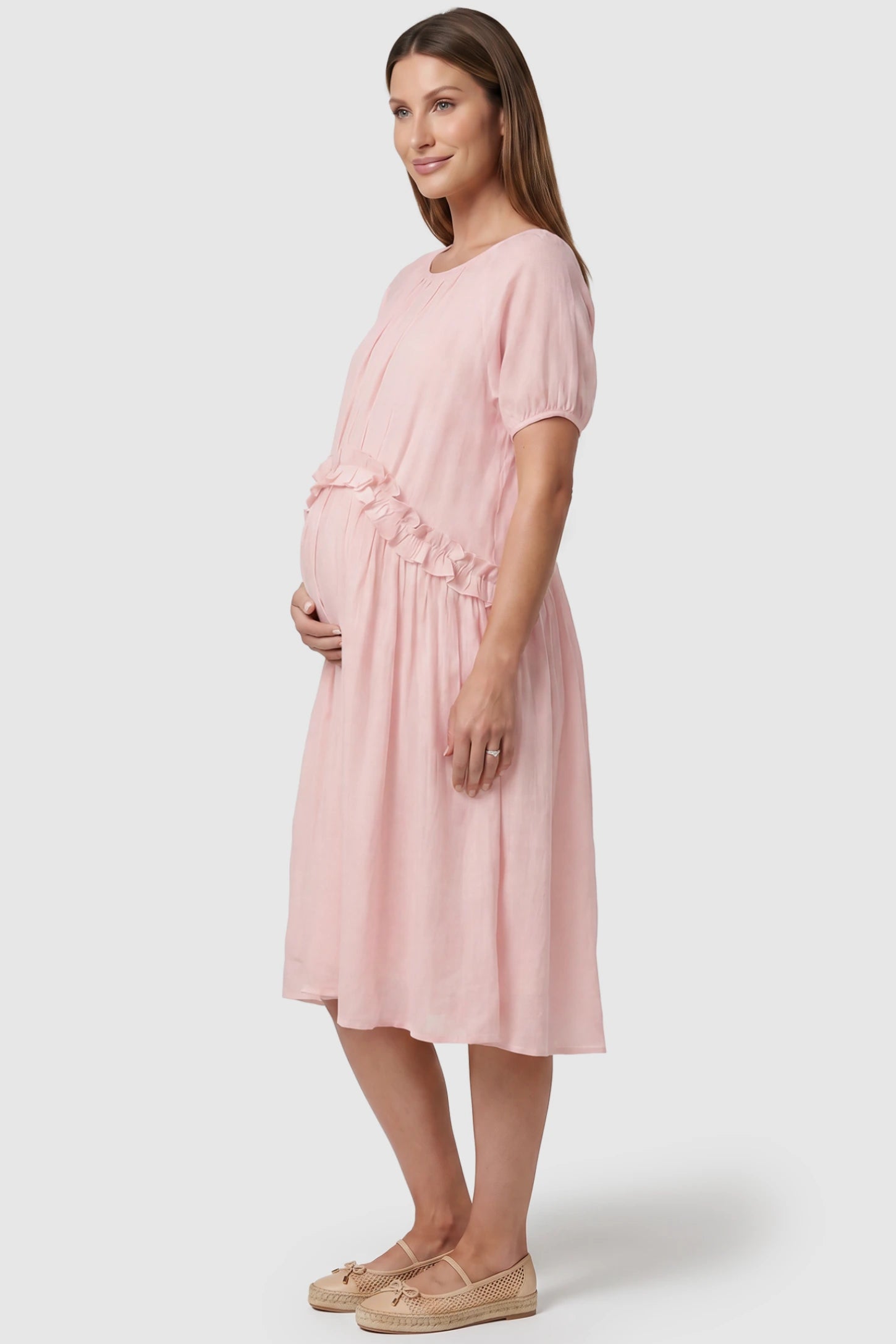 Round Neck Short Sleeve Flowy Maternity Midi Dress Round Neck Short Sleeve Flowy Maternity Midi Dress in Pink featuring ruffled waist on a pregnant model, side view.