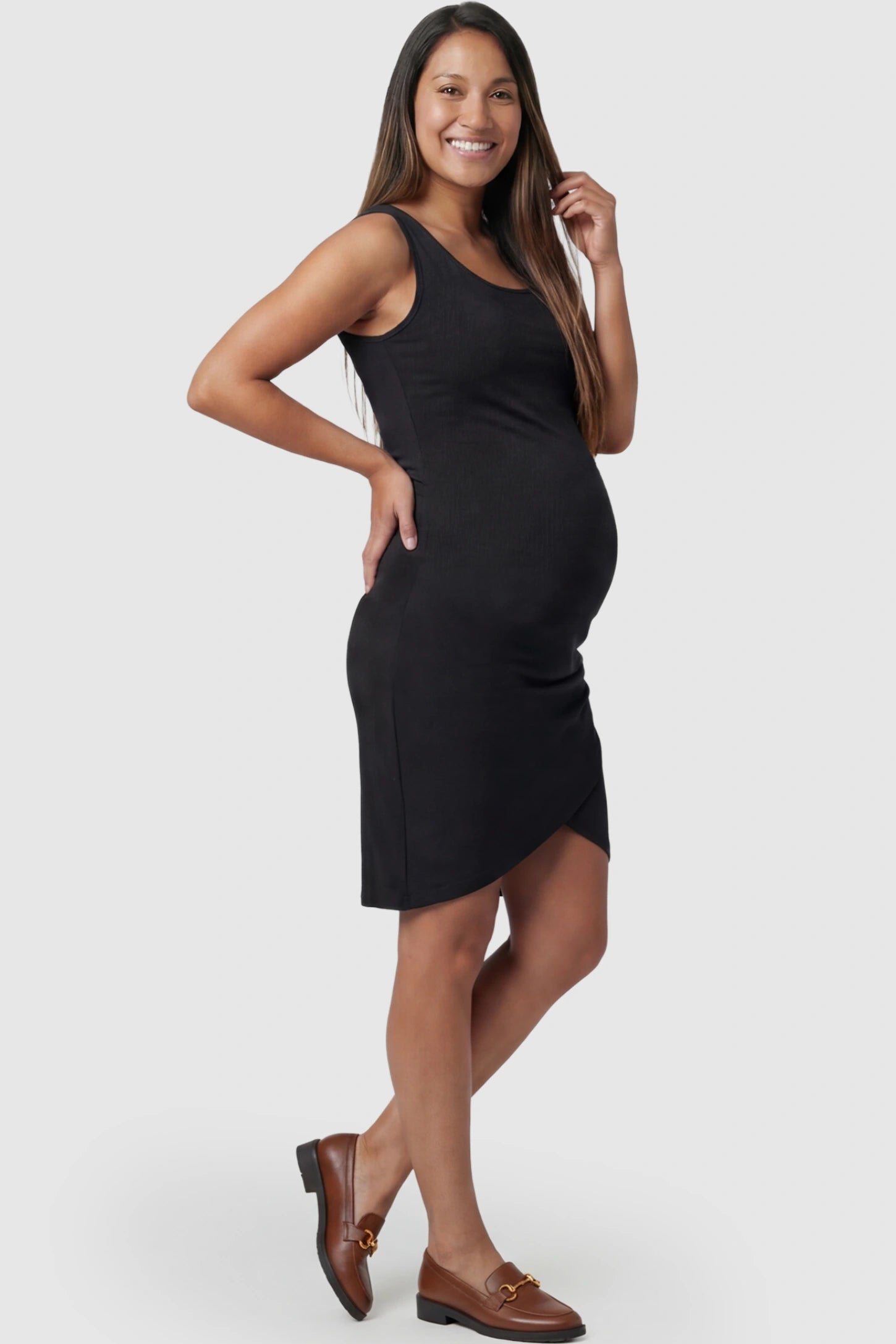 Ruched Tulip-Hem Sleeveless Bodycon Maternity Dress Ruched Tulip-Hem Bodycon Maternity Dress in Black featuring a side-ruched pencil skirt on a pregnant model posing side.