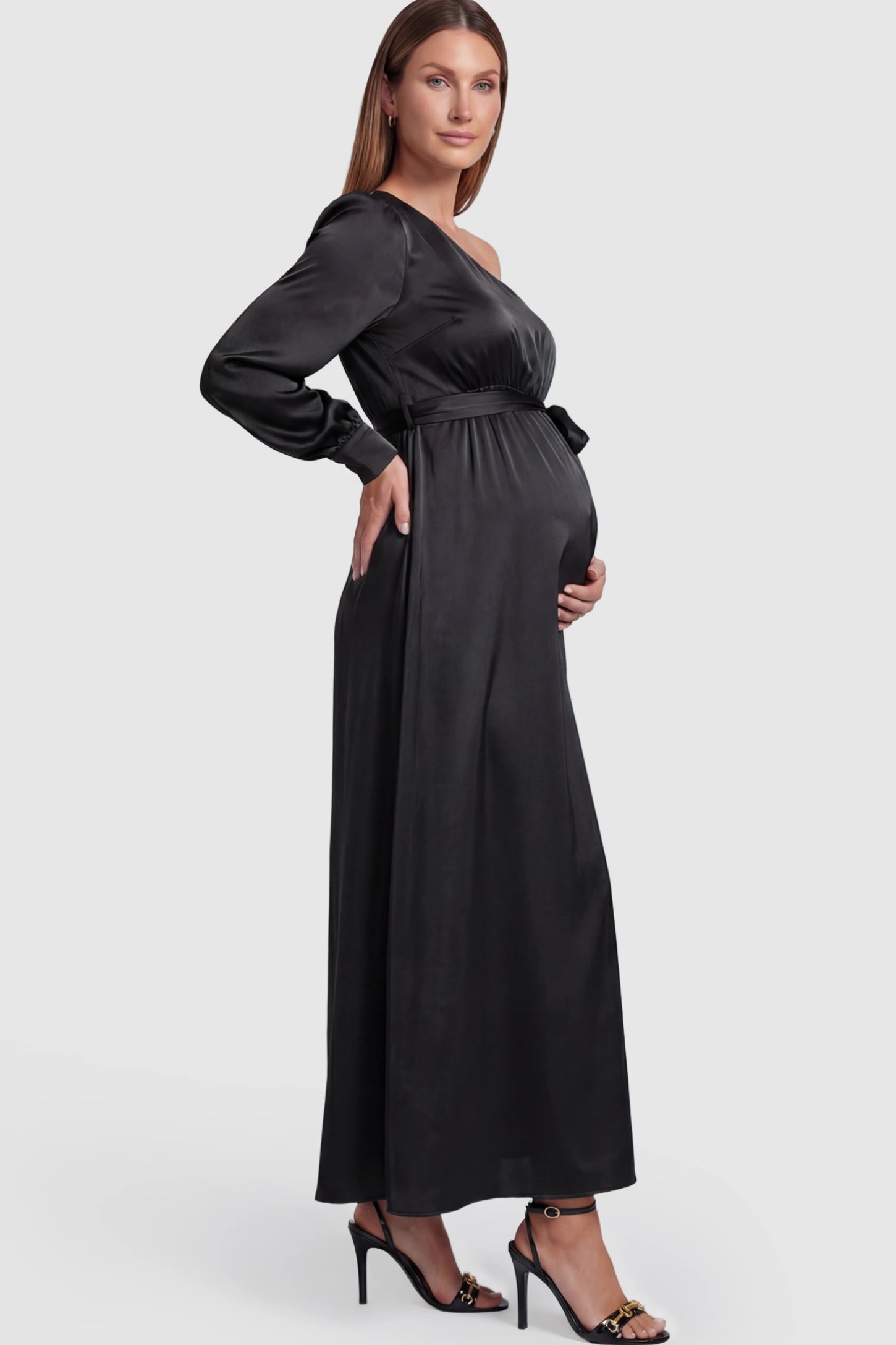 Satin One Shoulder Belted Maternity Maxi Dress Satin One-Shoulder Belted Maternity Maxi Dress in Black featuring a side slit and waist tie on a pregnant model showing side.