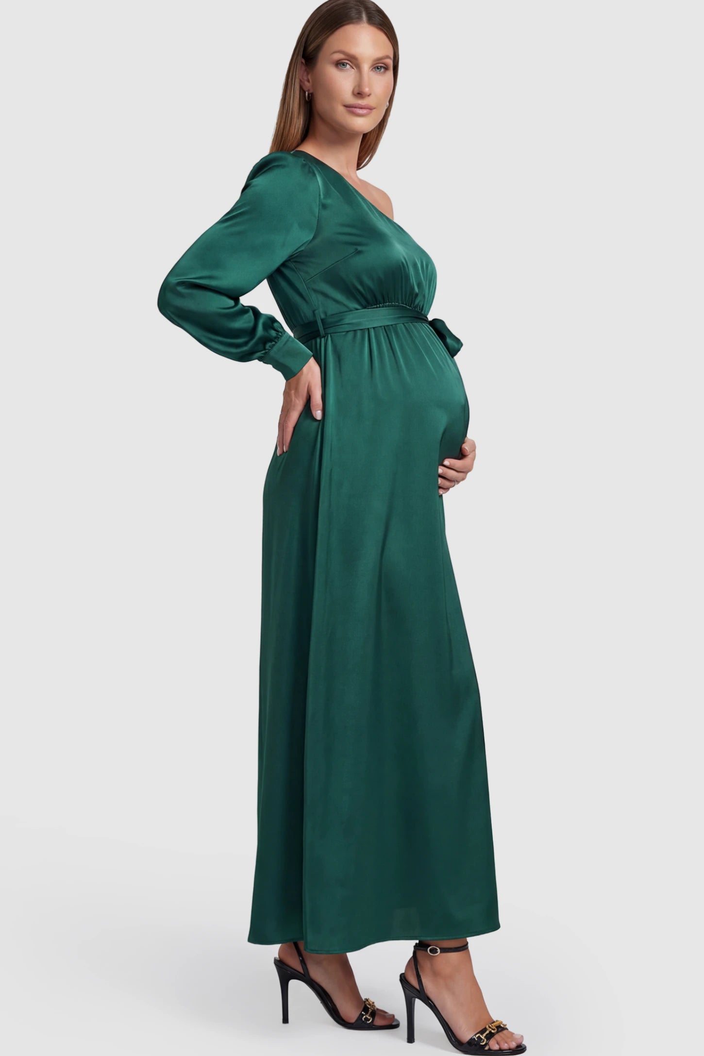 Satin One Shoulder Belted Maternity Maxi Dress Satin One-Shoulder Belted Maternity Maxi Dress in Green featuring a side slit and waist tie on a pregnant model showing side.