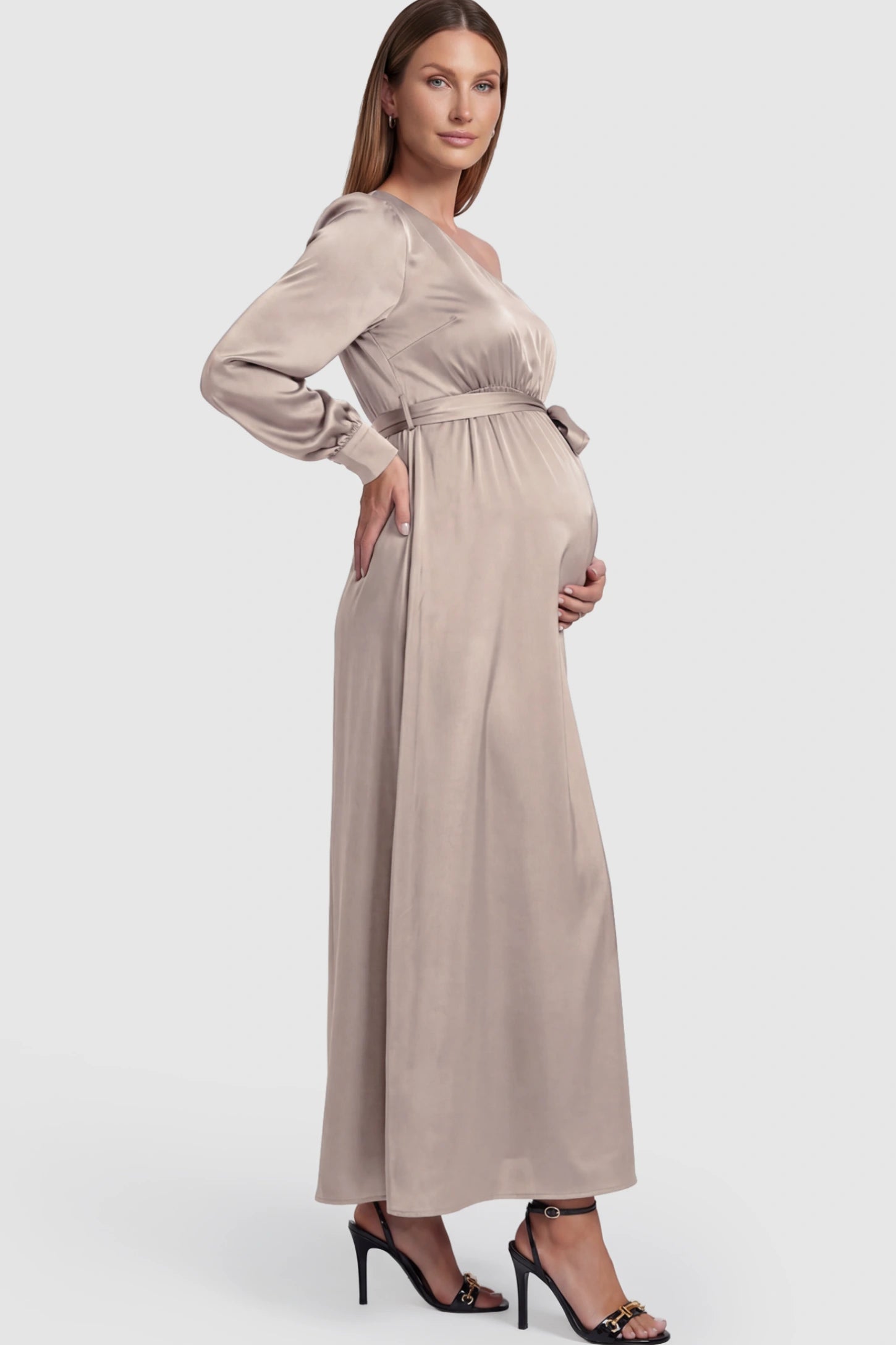 Satin One Shoulder Belted Maternity Maxi Dress Satin One-Shoulder Belted Maternity Maxi Dress in Light gray featuring a side slit and waist tie on a pregnant model showing side.