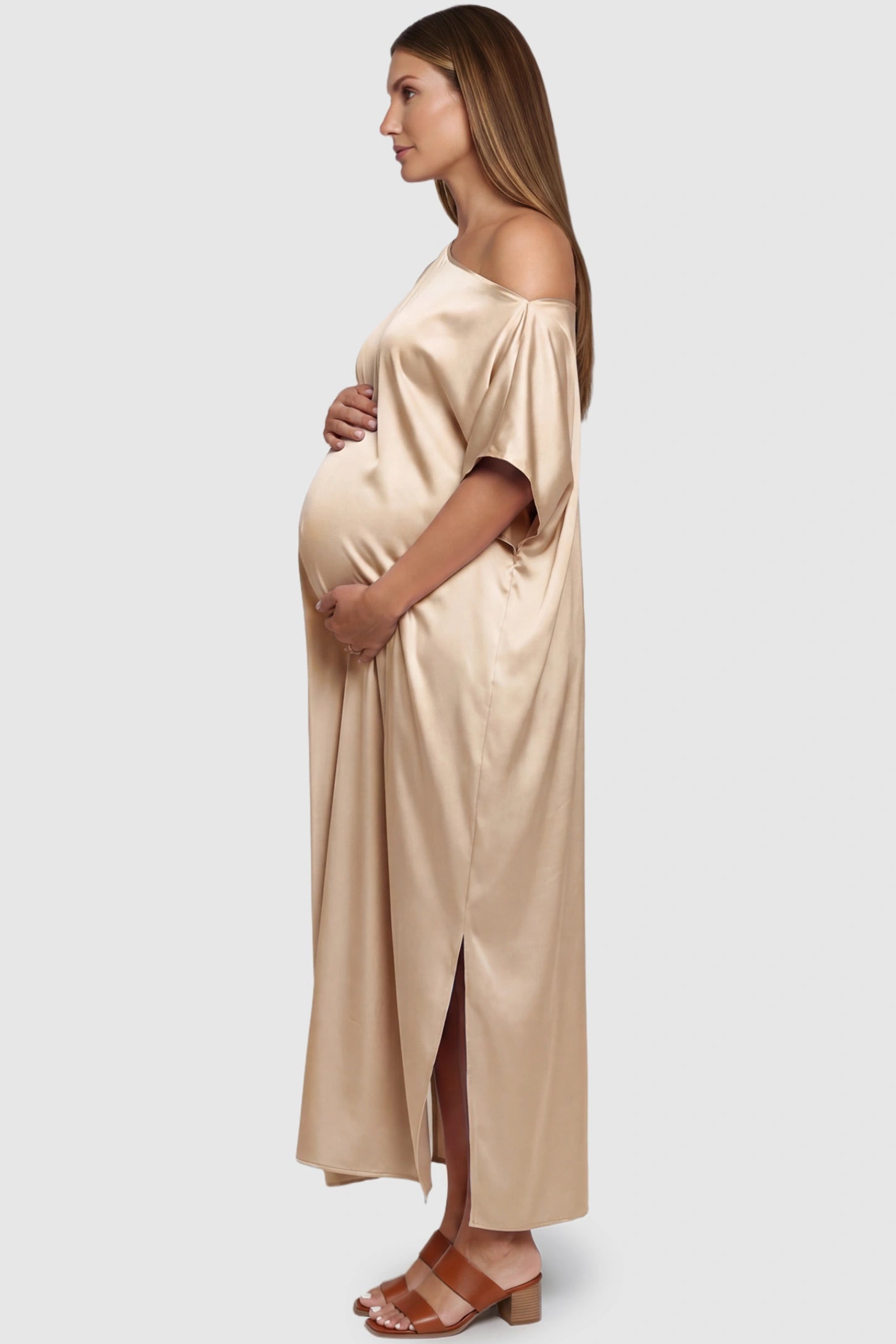 Satin One Shoulder Side Slit Maternity Maxi Dress Satin One Shoulder Side Slit Maternity Maxi Dress in Apricot featuring a draped batwing sleeve on a pregnant model, side view.