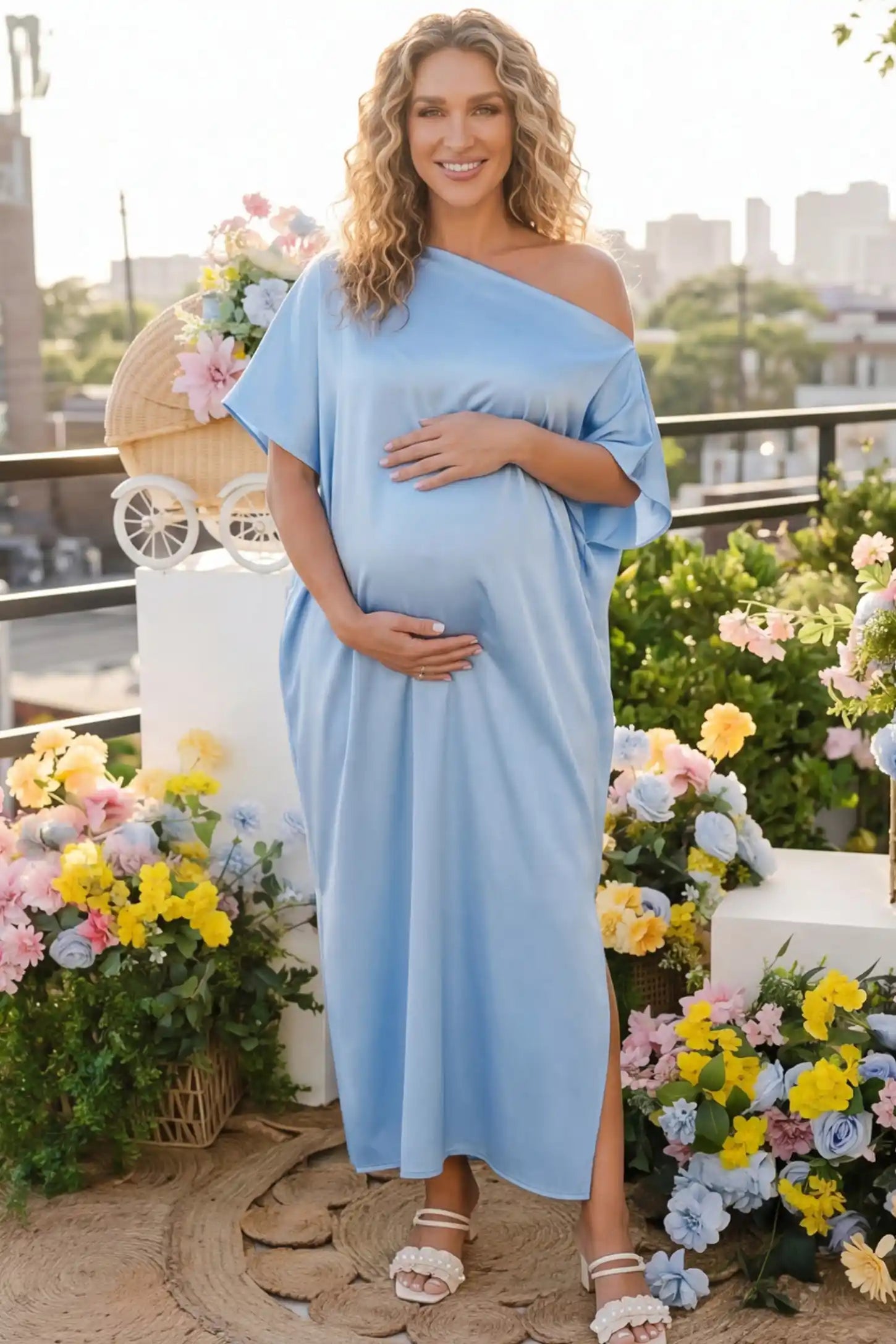Satin One Shoulder Side Slit Maternity Maxi Dress Satin One Shoulder Side Slit Maternity Maxi Dress in Blue featuring a draped batwing sleeve on a pregnant woman in outdoor setting, front view.
