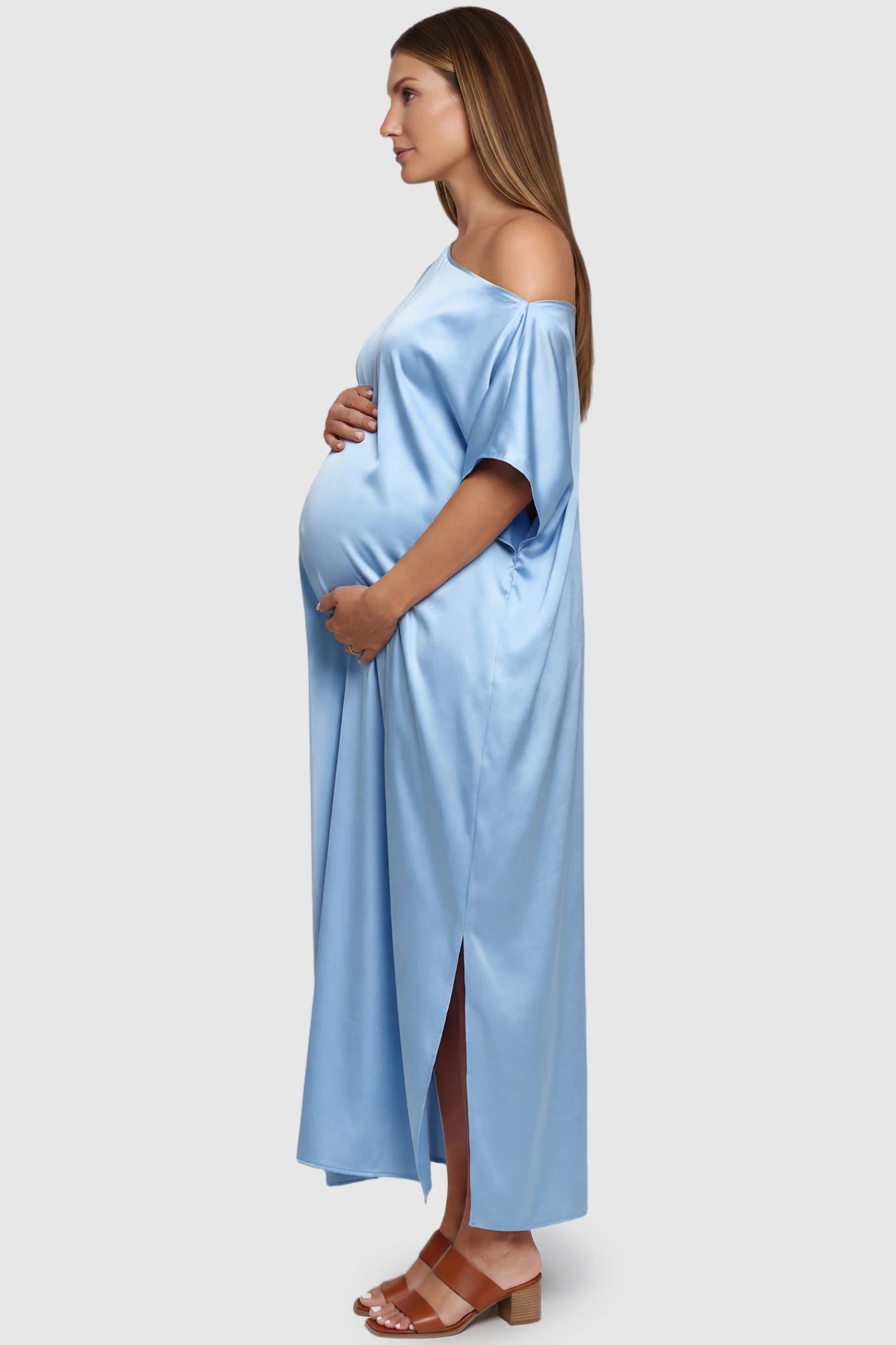 Satin One Shoulder Side Slit Maternity Maxi Dress Satin One Shoulder Side Slit Maternity Maxi Dress in Blue featuring a draped batwing sleeve on a pregnant model, side view.
