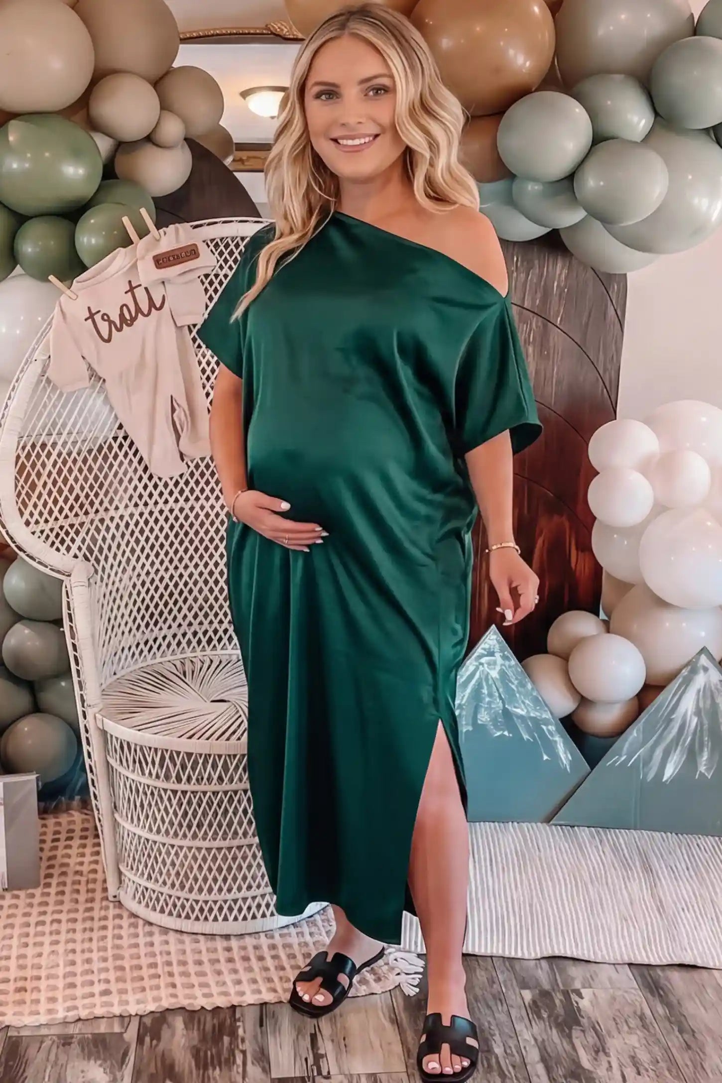 Satin One Shoulder Side Slit Maternity Maxi Dress Satin One Shoulder Side Slit Maternity Maxi Dress in Dark Green featuring a draped batwing sleeve on a pregnant woman in indoor setting, front view.