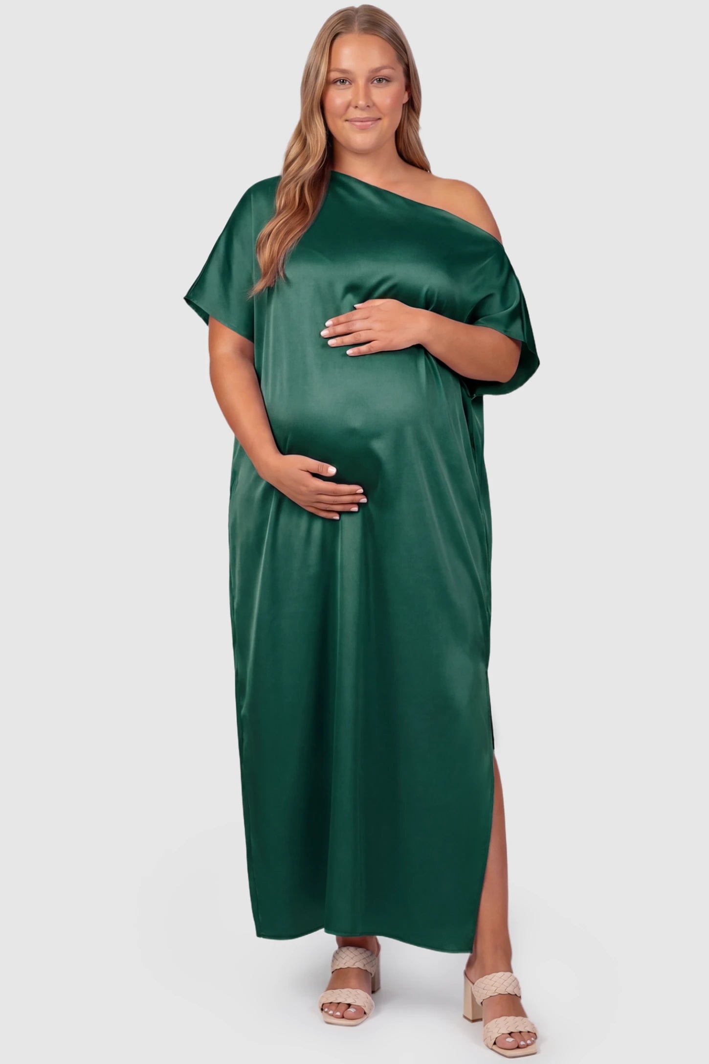 Satin One Shoulder Side Slit Maternity Maxi Dress Satin One Shoulder Side Slit Maternity Maxi Dress in Dark Green featuring a draped batwing sleeve on a plus size pregnant model, front view.