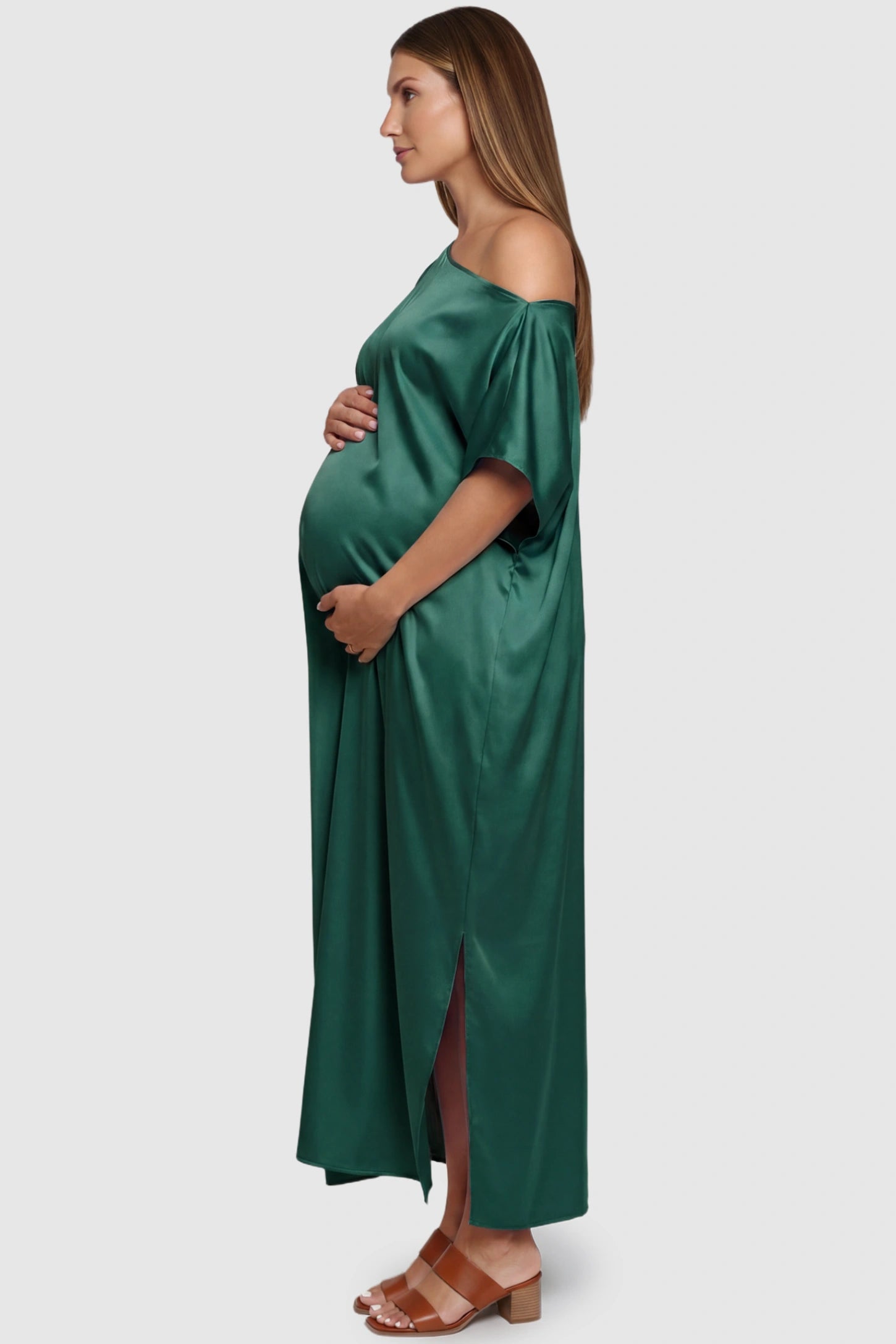 Satin One Shoulder Side Slit Maternity Maxi Dress Satin One Shoulder Side Slit Maternity Maxi Dress in Dark Green featuring a draped batwing sleeve on a pregnant model, side view.