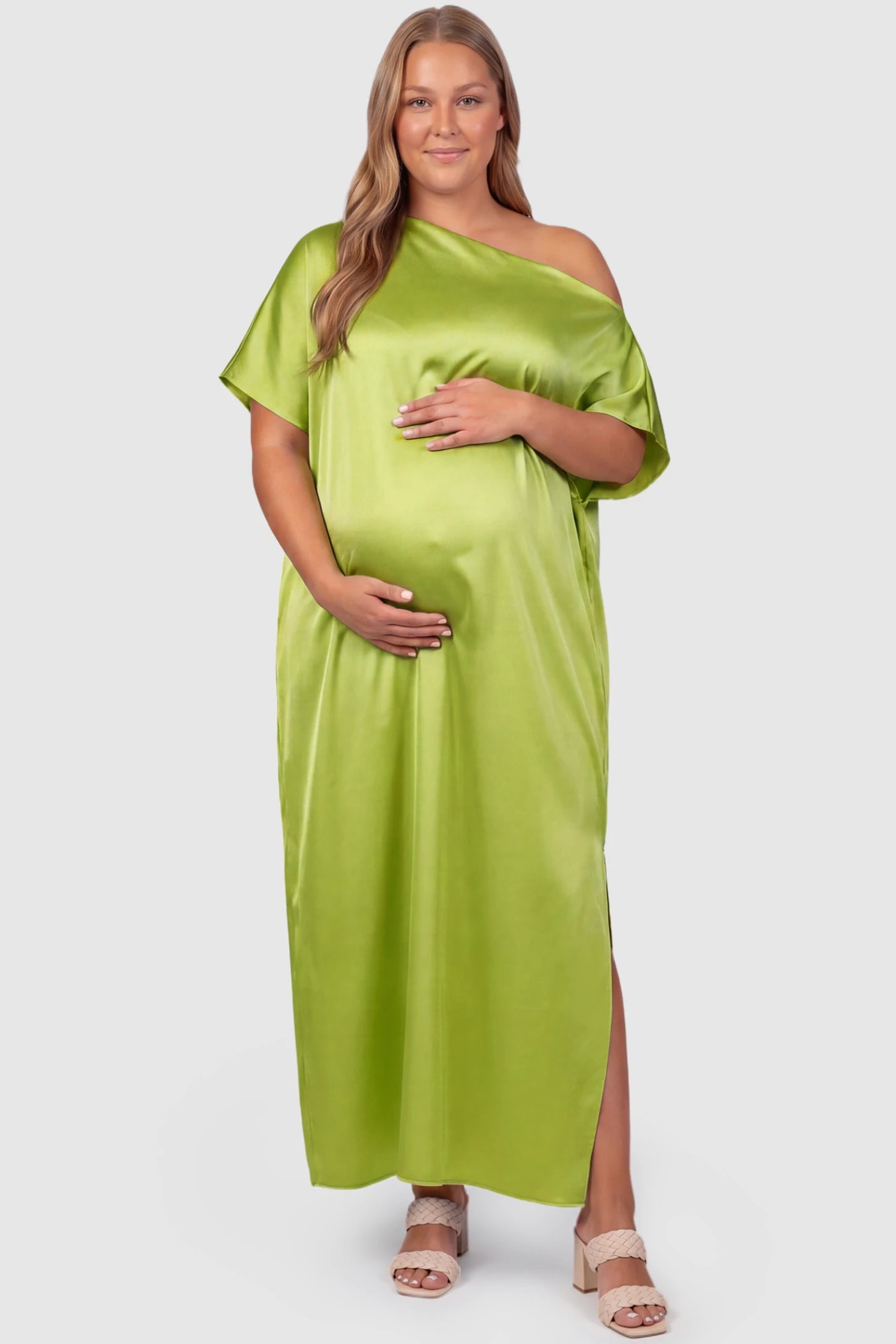 Satin One Shoulder Side Slit Maternity Maxi Dress Satin One Shoulder Side Slit Maternity Maxi Dress in Green featuring a draped batwing sleeve on a plus size pregnant model, front view.