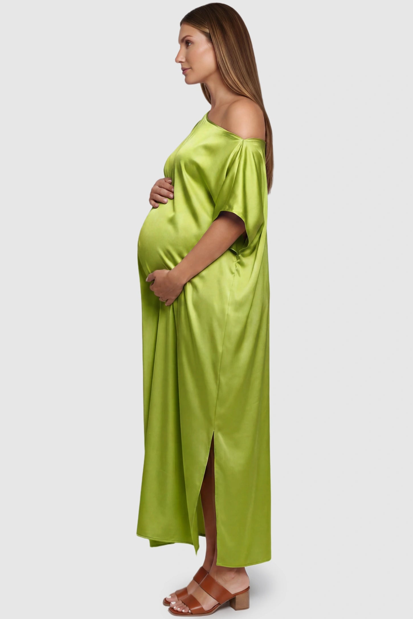 Satin One Shoulder Side Slit Maternity Maxi Dress Satin One Shoulder Side Slit Maternity Maxi Dress in Green featuring a draped batwing sleeve on a pregnant model, side view.