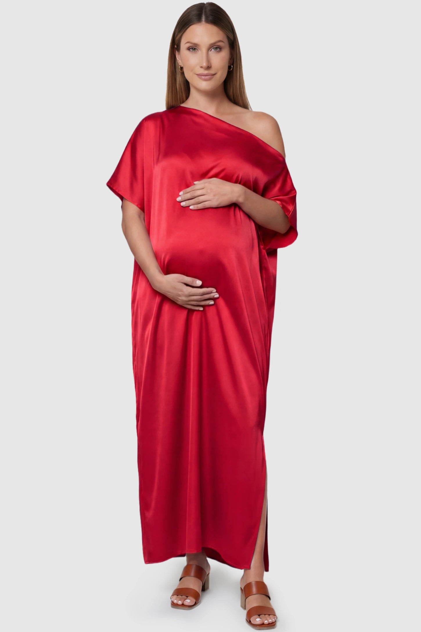 Satin One Shoulder Side Slit Maternity Maxi Dress Satin One Shoulder Side Slit Maternity Maxi Dress in Red featuring a draped batwing sleeve on a pregnant model, front view.