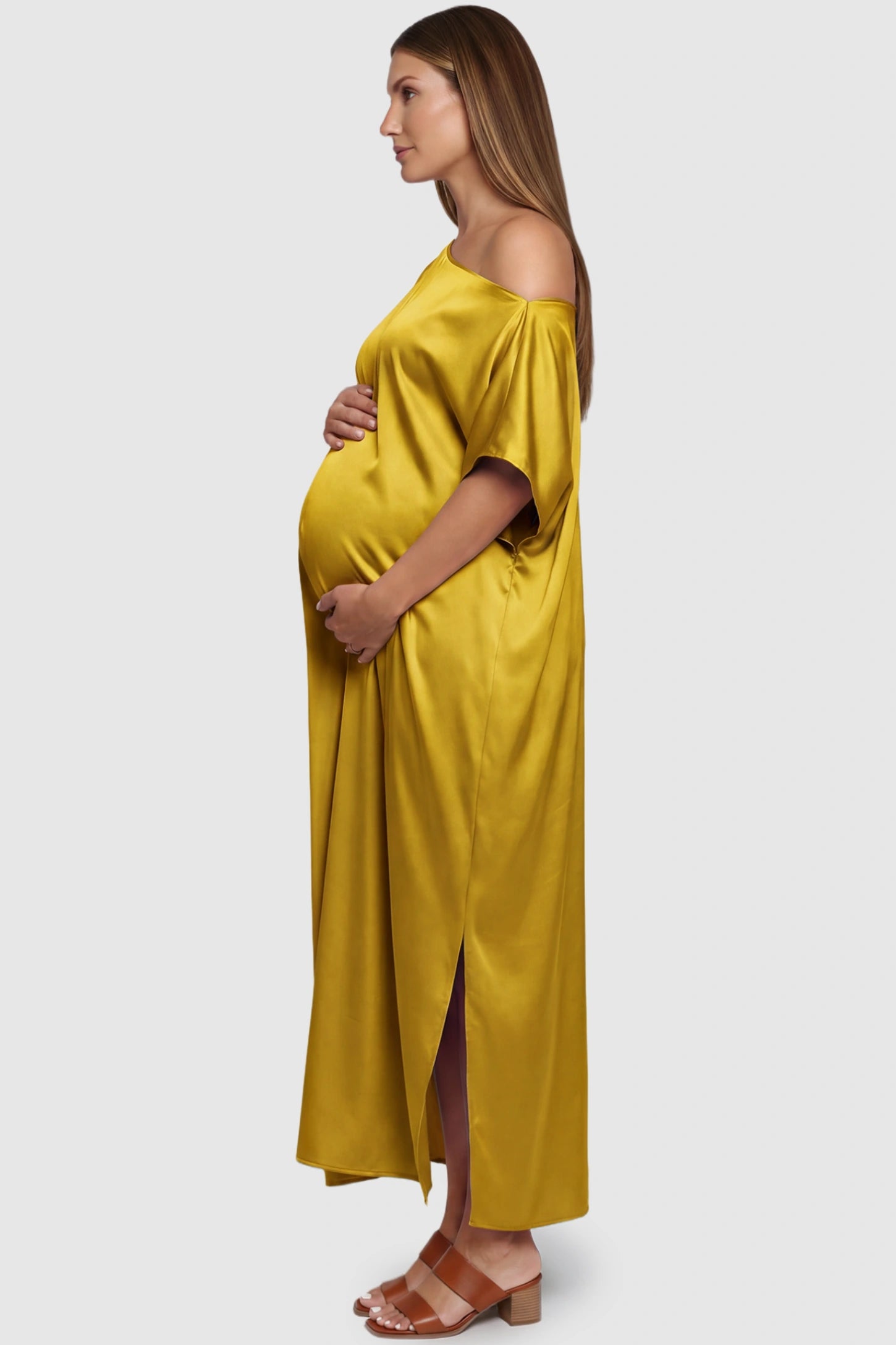 Satin One Shoulder Side Slit Maternity Maxi Dress Satin One Shoulder Side Slit Maternity Maxi Dress in Yellow featuring a draped batwing sleeve on a pregnant model, side view.