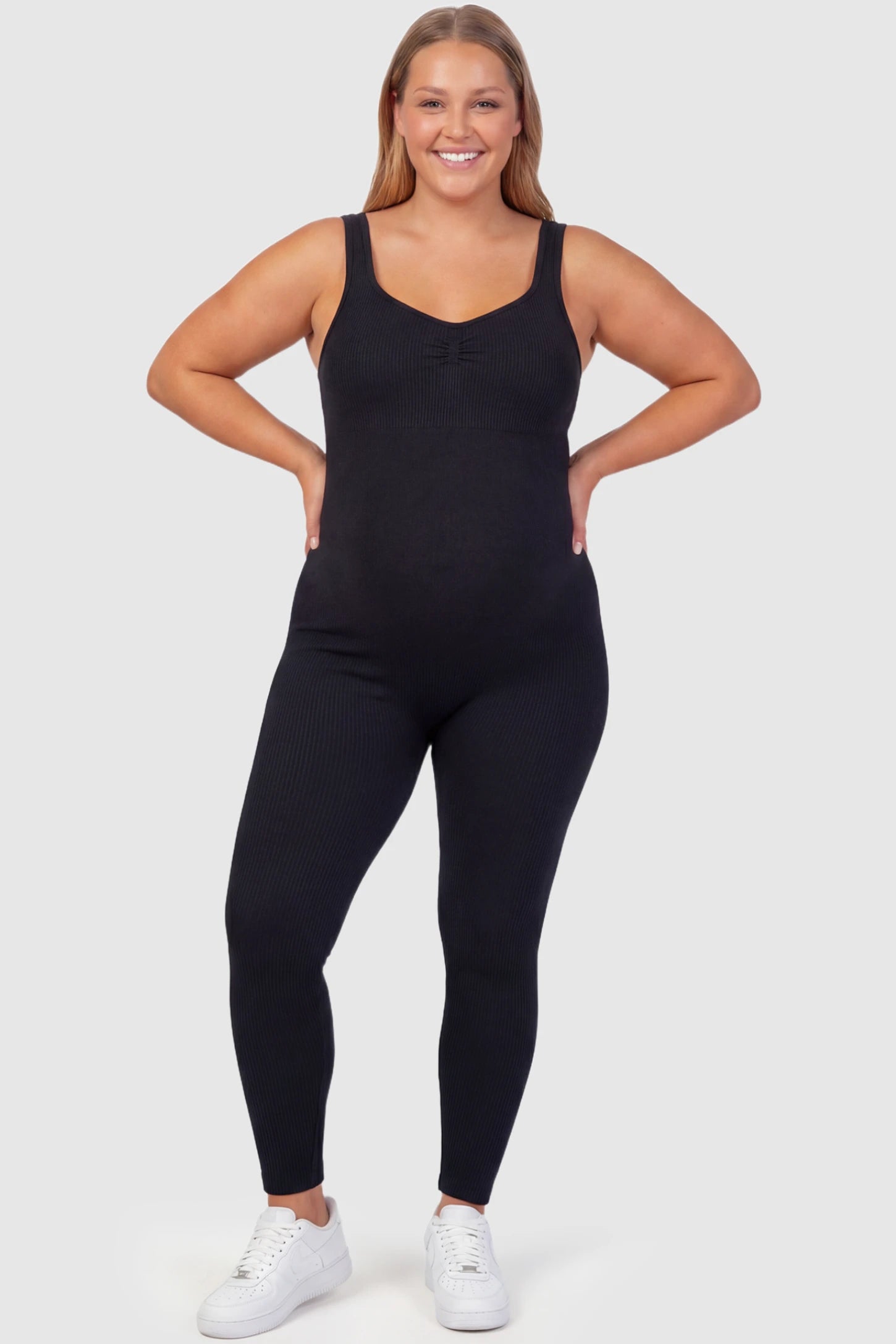Scoop Neck Sleeveless Ribbed Bodycon Maternity Jumpsuit Scoop Neck Sleeveless Ribbed Bodycon Maternity Jumpsuit in Black featuring ribbed knit texture on a plus size pregnant model, front view.