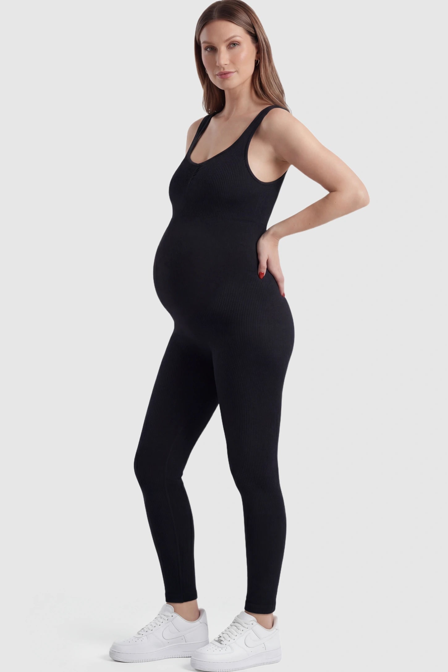 Scoop Neck Sleeveless Ribbed Bodycon Maternity Jumpsuit Scoop Neck Sleeveless Ribbed Bodycon Maternity Jumpsuit in Black featuring ribbed knit texture on a pregnant model showing side.