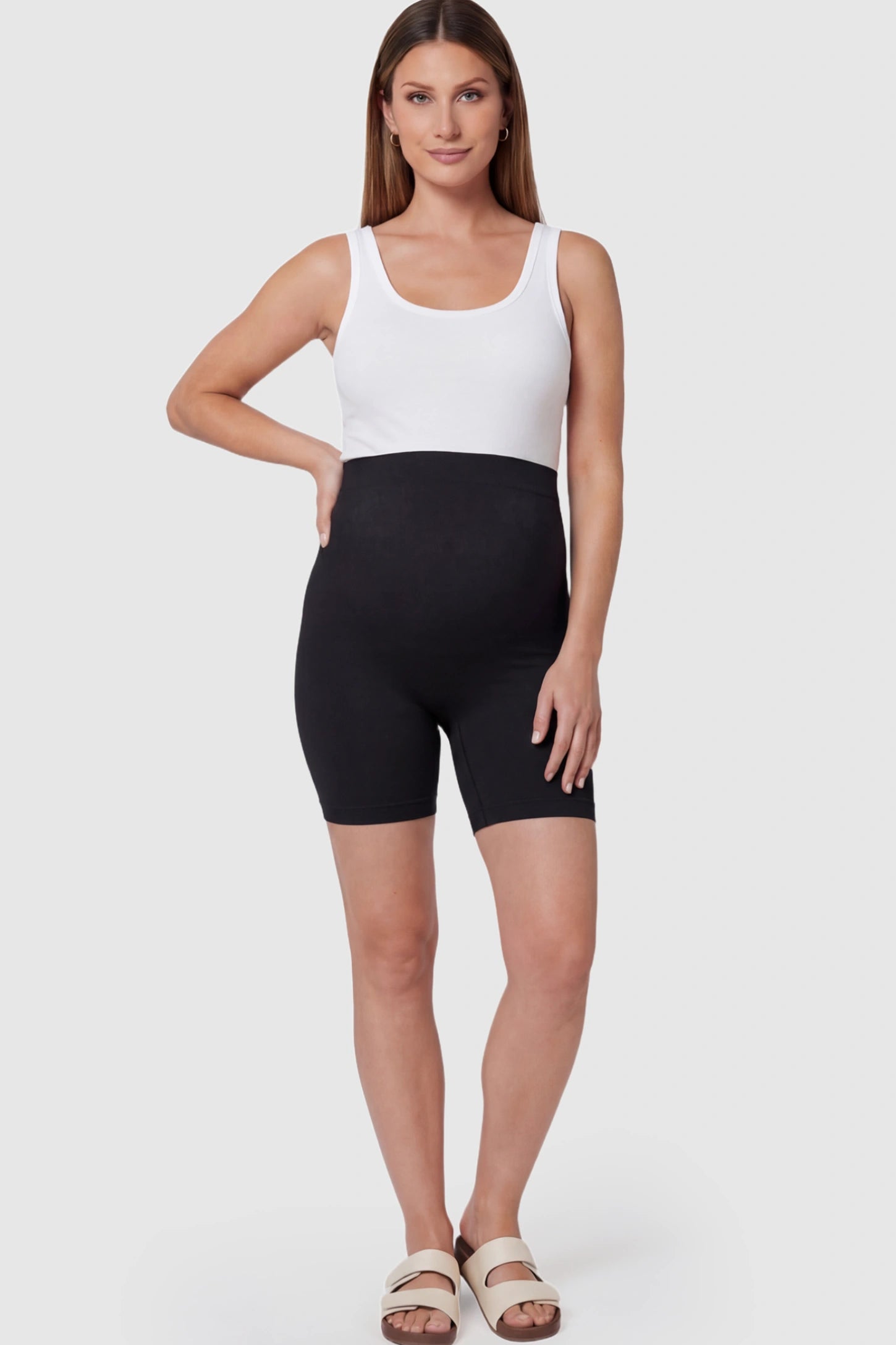 Seamless High Waisted Maternity Shapewear Shorts Seamless High-Waisted Mid Thigh Maternity Shapewear Shorts in Black featuring a smooth belly support panel on a pregnant model.