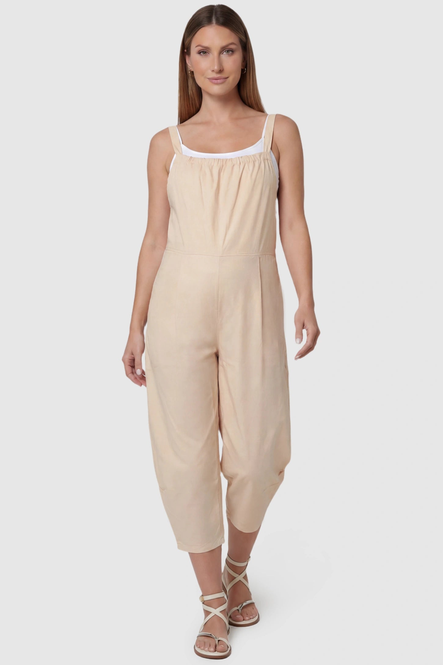Sleeveless Balloon-Leg Maternity Jumpsuit in Beige featuring deep side pockets on a pregnant model, front view.