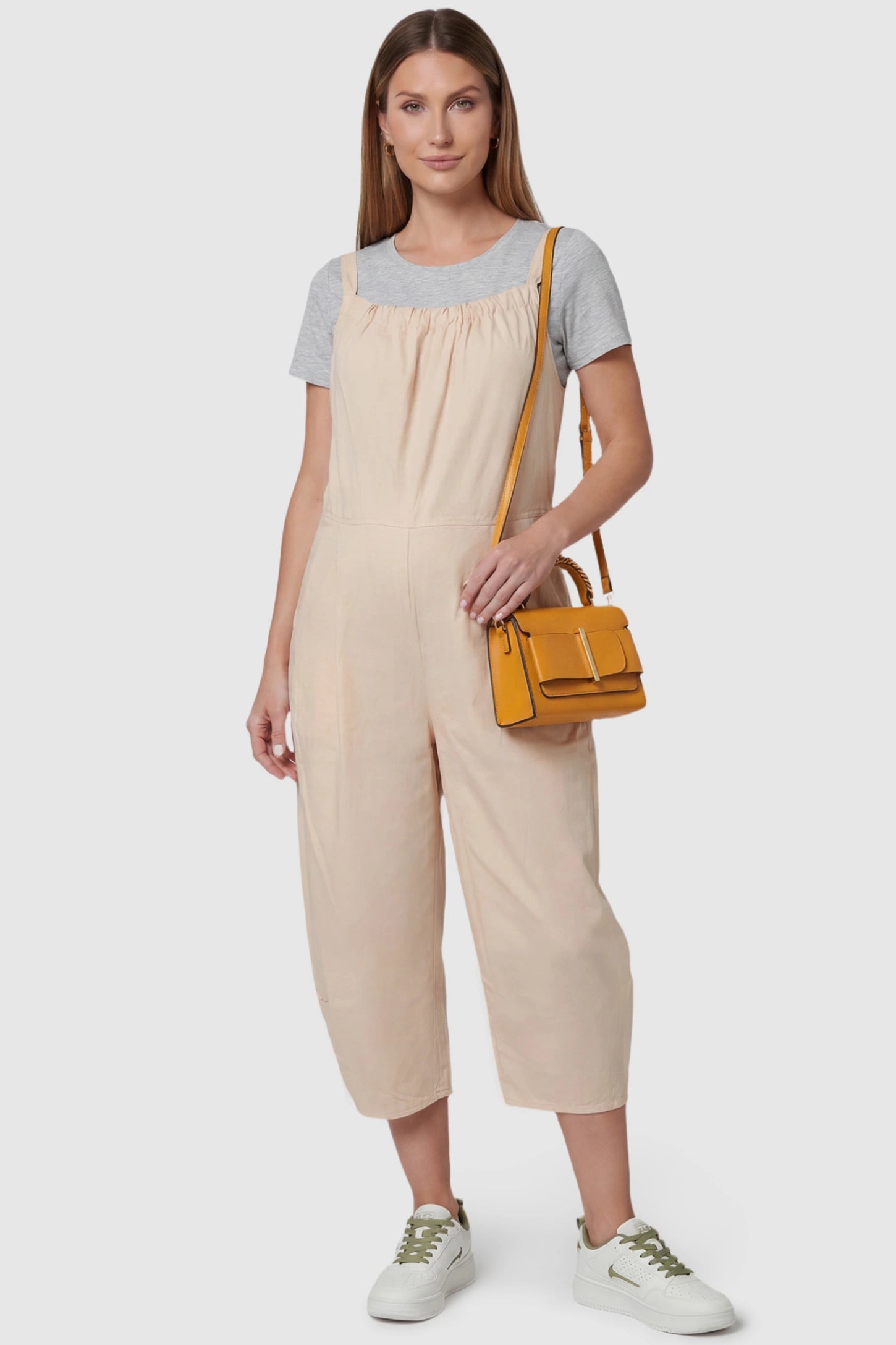 Sleeveless Balloon-Leg Maternity Jumpsuit in Beige featuring deep side pockets on a pregnant model, front view.