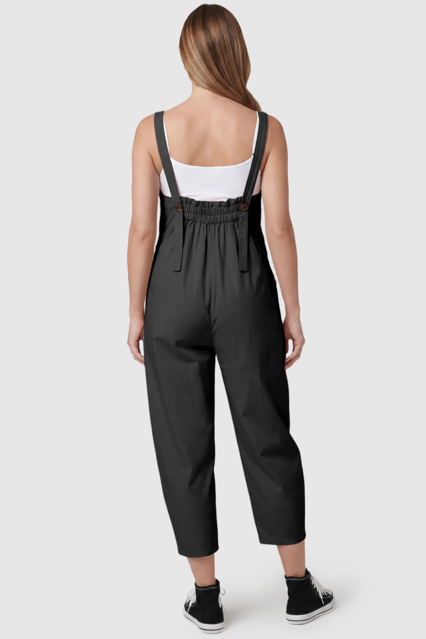 Sleeveless Balloon-Leg Maternity Jumpsuit Sleeveless Balloon-Leg Maternity Jumpsuit in Black featuring an elasticated back and buttoned straps on a pregnant model, back view.