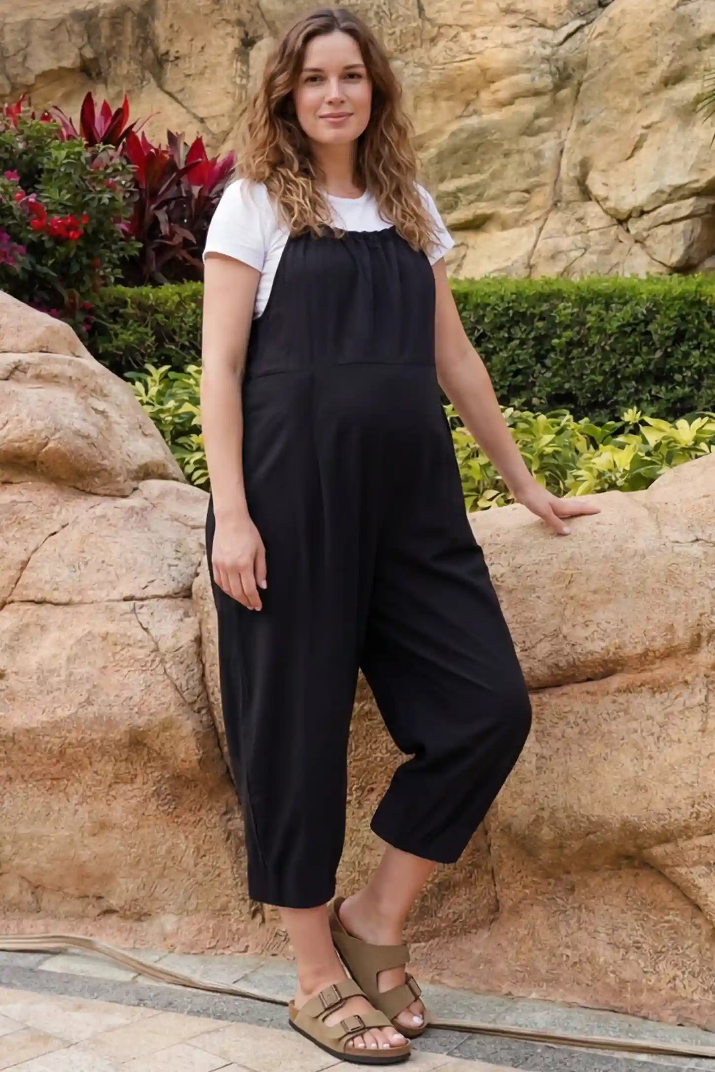 Sleeveless Balloon-Leg Maternity Jumpsuit Sleeveless Balloon-Leg Maternity Jumpsuit in Black featuring deep side pockets on a pregnant woman in outdoor setting, front view.