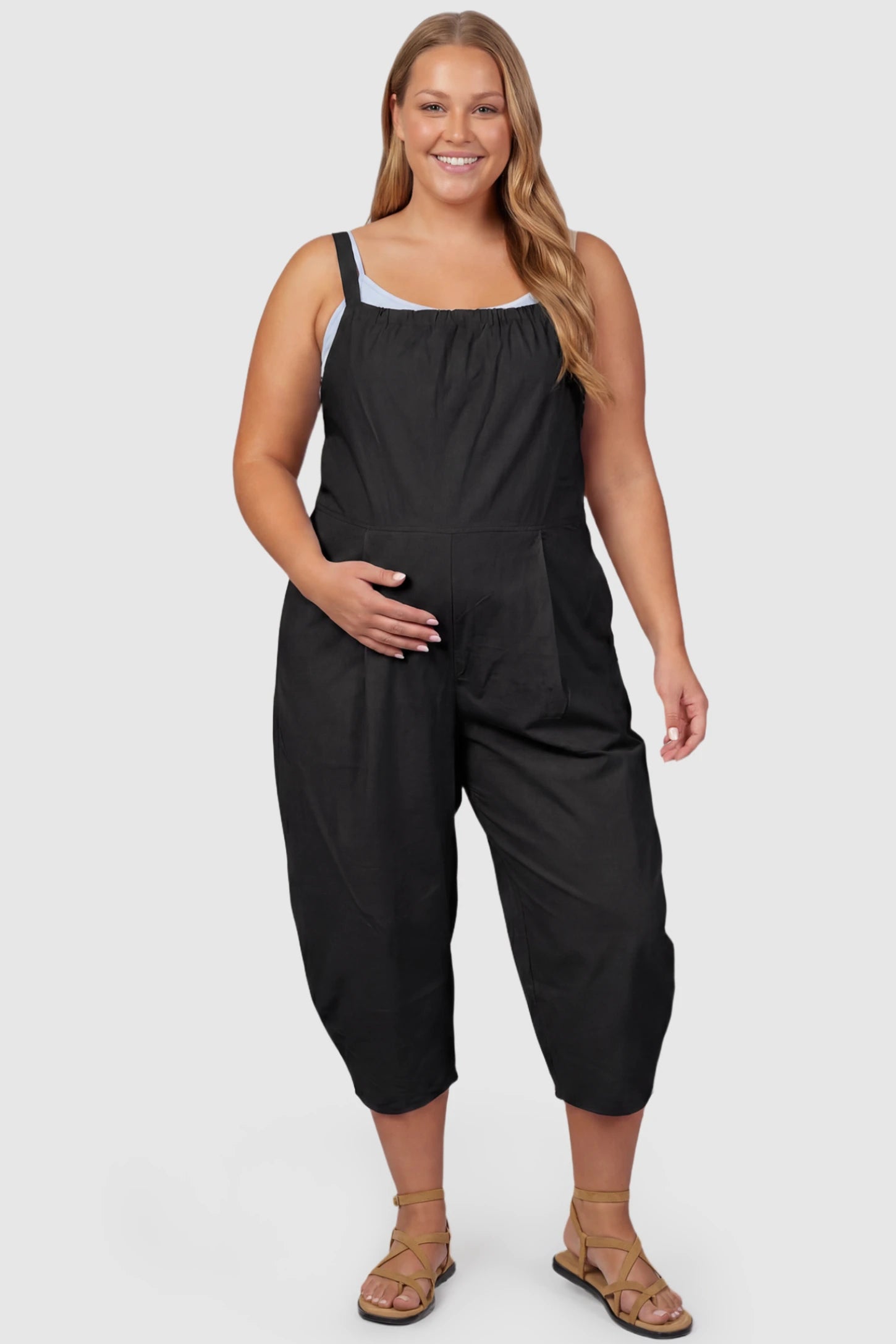 Sleeveless Balloon-Leg Maternity Jumpsuit Sleeveless Balloon-Leg Maternity Jumpsuit in Black featuring deep side pockets on a plus size pregnant model, front view.