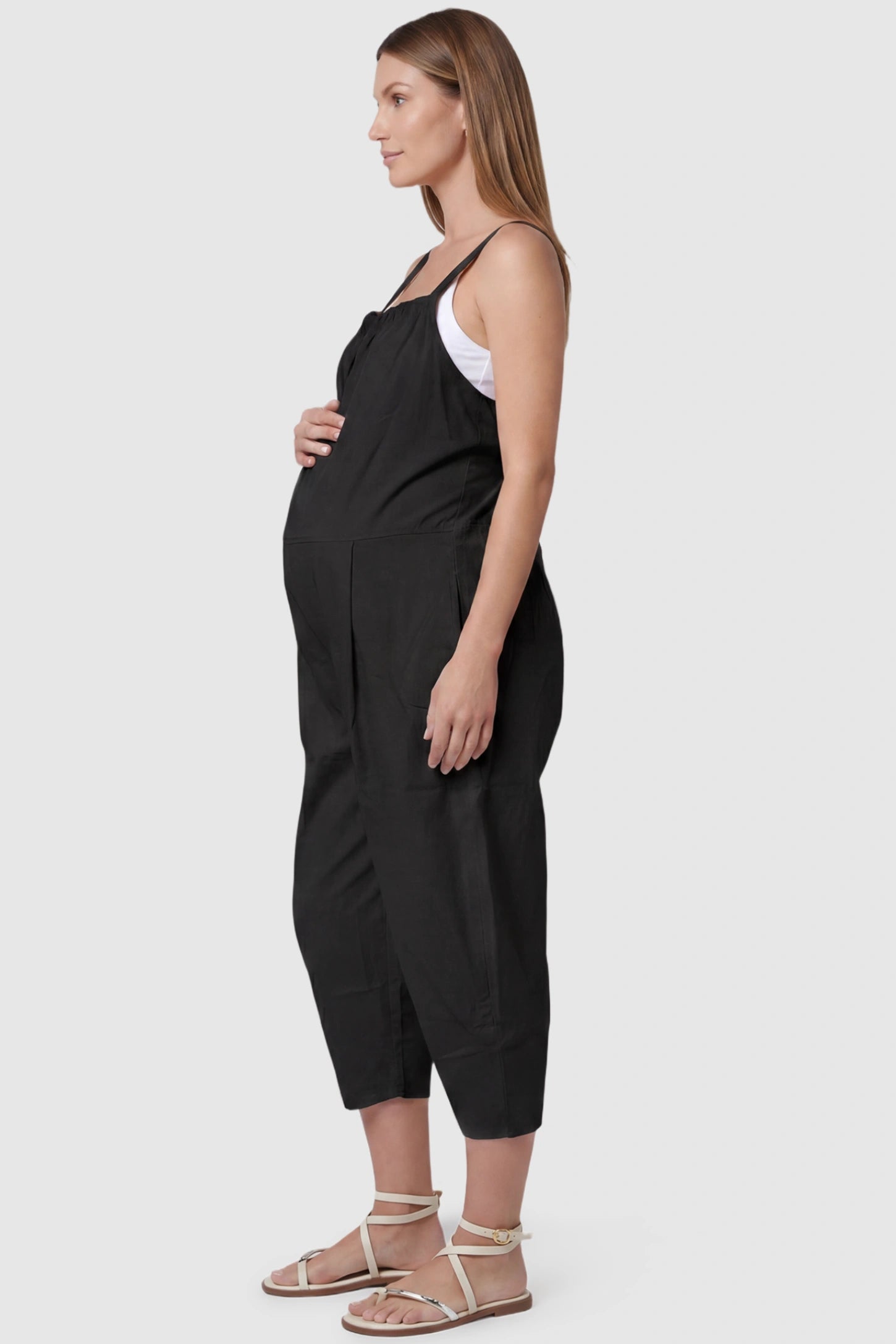 Sleeveless Balloon-Leg Maternity Jumpsuit Sleeveless Balloon-Leg Maternity Jumpsuit in Black featuring deep side pockets on a pregnant model, side view.