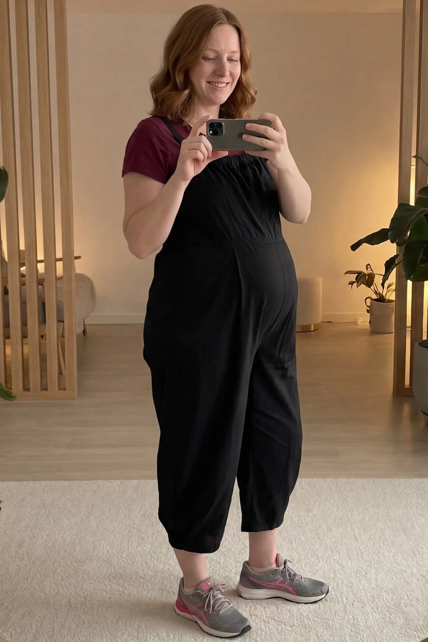 Sleeveless Balloon-Leg Maternity Jumpsuit Sleeveless Balloon-Leg Maternity Jumpsuit in Black featuring deep side pockets on a pregnant woman in indoor setting, side view.
