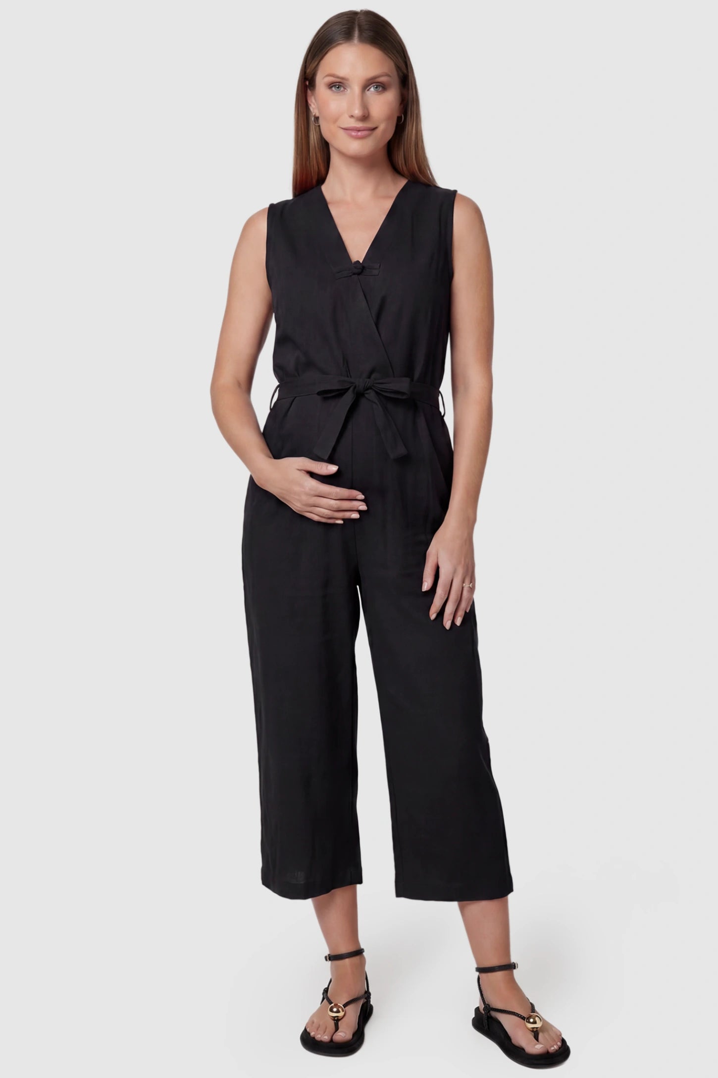 Sleeveless V-Neck Tie-Waist Maternity Jumpsuit Sleeveless V-Neck Tie-Waist Maternity Jumpsuit in Black featuring a relaxed wide-leg design on a pregnant model, front view.