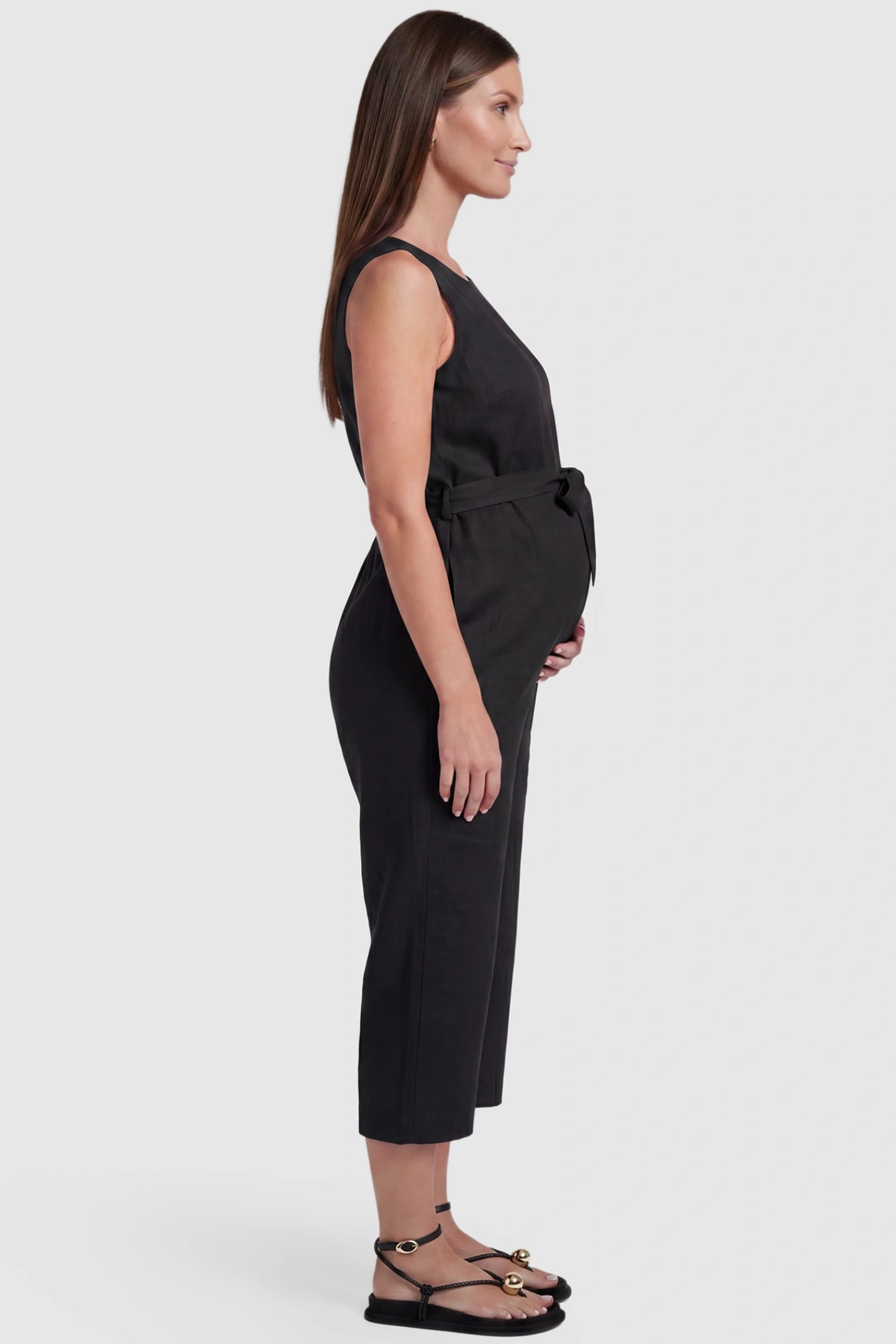 Sleeveless V-Neck Tie-Waist Maternity Jumpsuit Sleeveless V-Neck Tie-Waist Maternity Jumpsuit in Black featuring a relaxed wide-leg design on a pregnant model, side view.