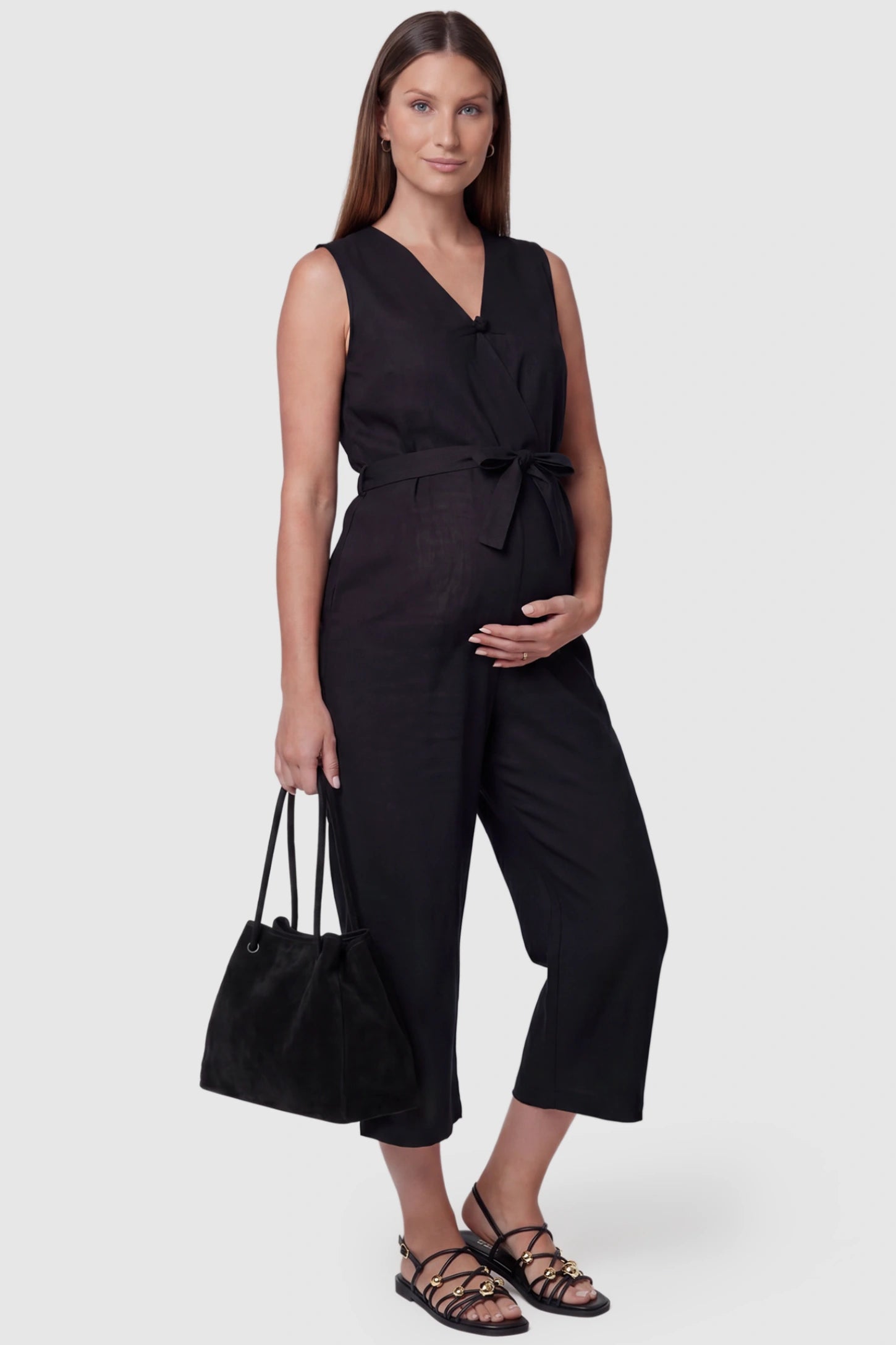 Sleeveless V-Neck Tie-Waist Maternity Jumpsuit Sleeveless V-Neck Tie-Waist Maternity Jumpsuit in Black featuring a relaxed wide-leg design on a pregnant model, side view.