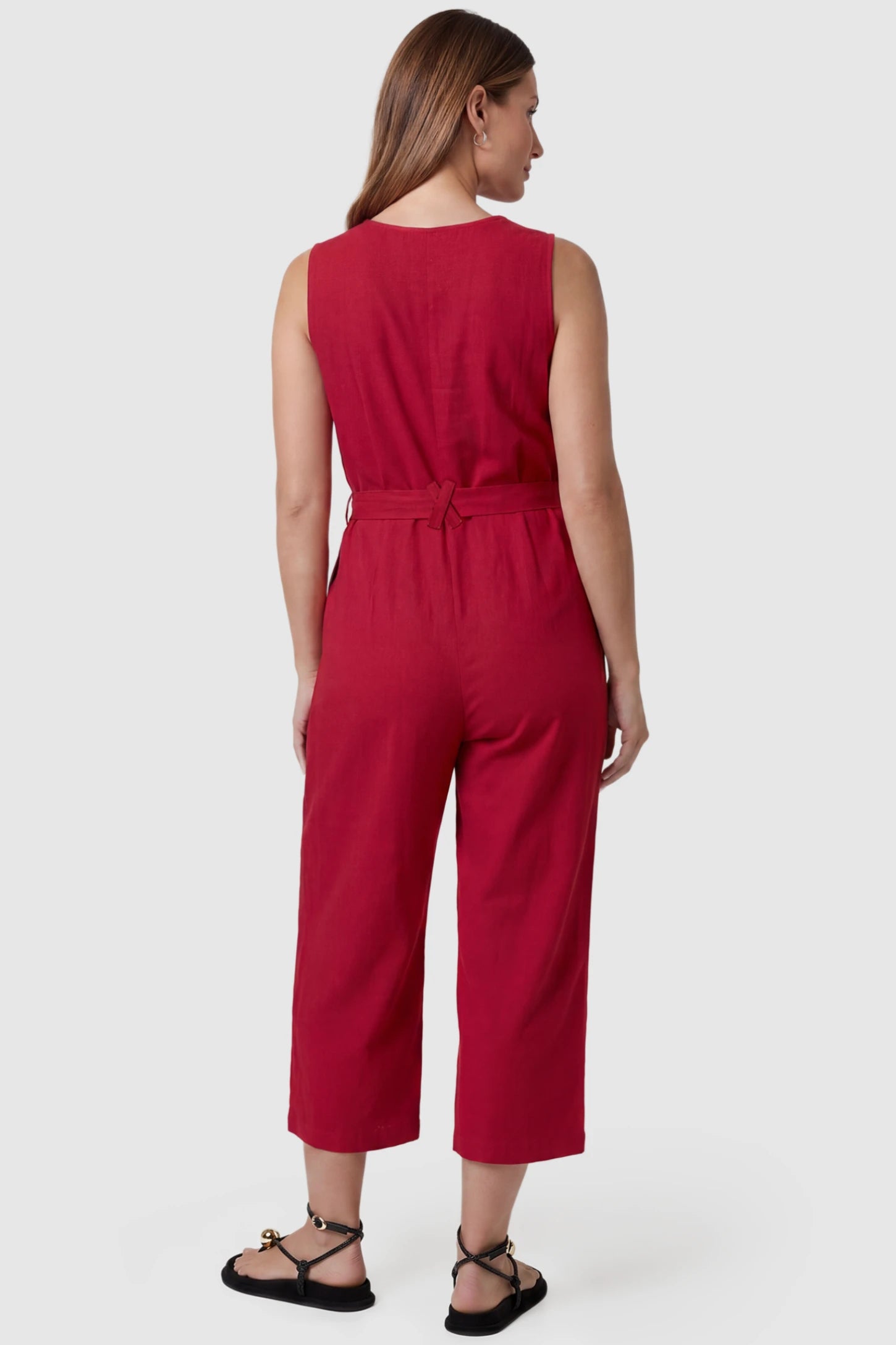 Sleeveless V-Neck Tie-Waist Maternity Jumpsuit Sleeveless V-Neck Tie-Waist Maternity Jumpsuit in Red featuring a relaxed wide-leg design on a pregnant model, back view.