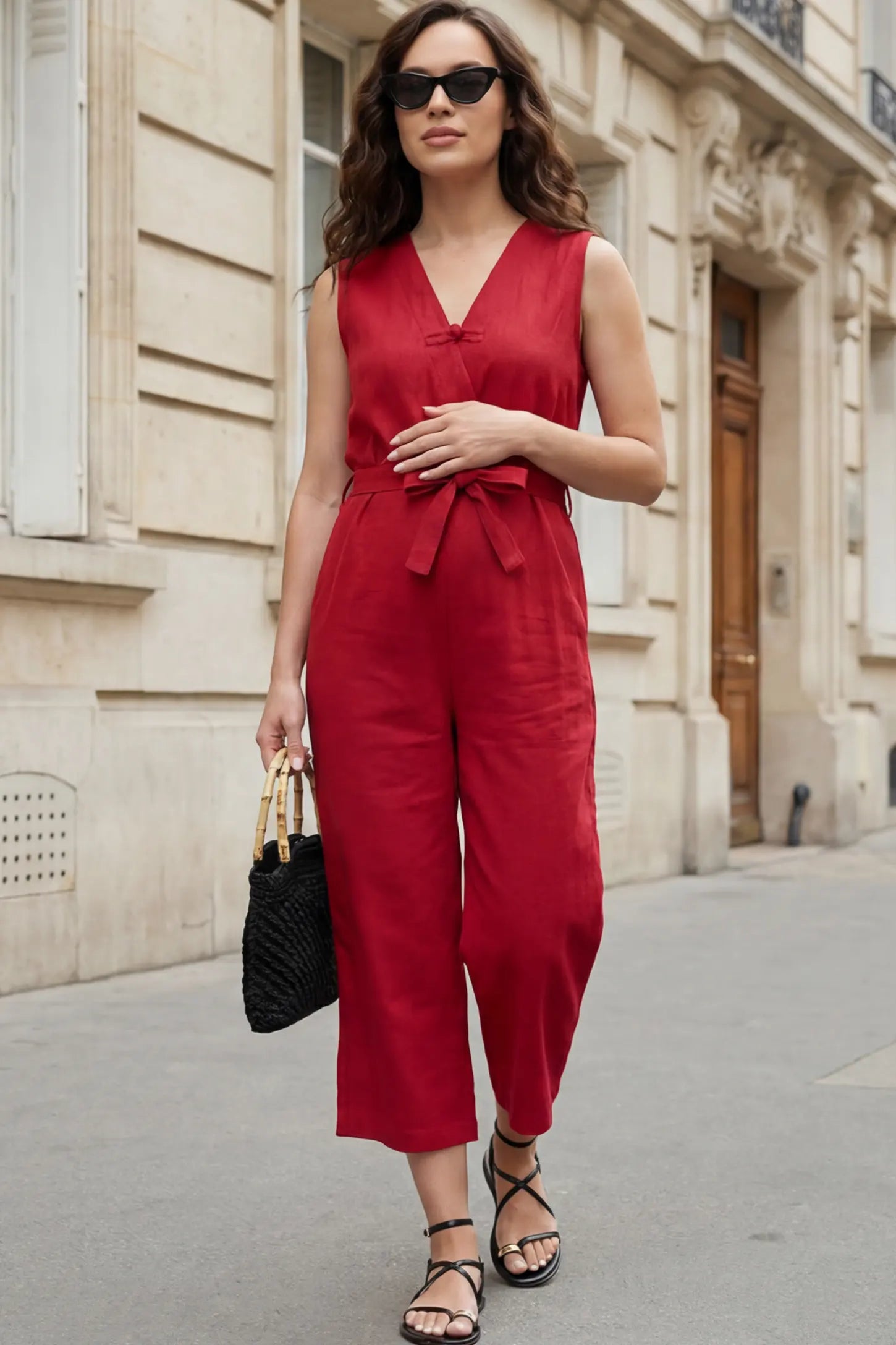 Sleeveless V-Neck Tie-Waist Maternity Jumpsuit Sleeveless V-Neck Tie-Waist Maternity Jumpsuit in Red featuring a relaxed wide-leg design on a pregnant woman in outdoor setting, front view.